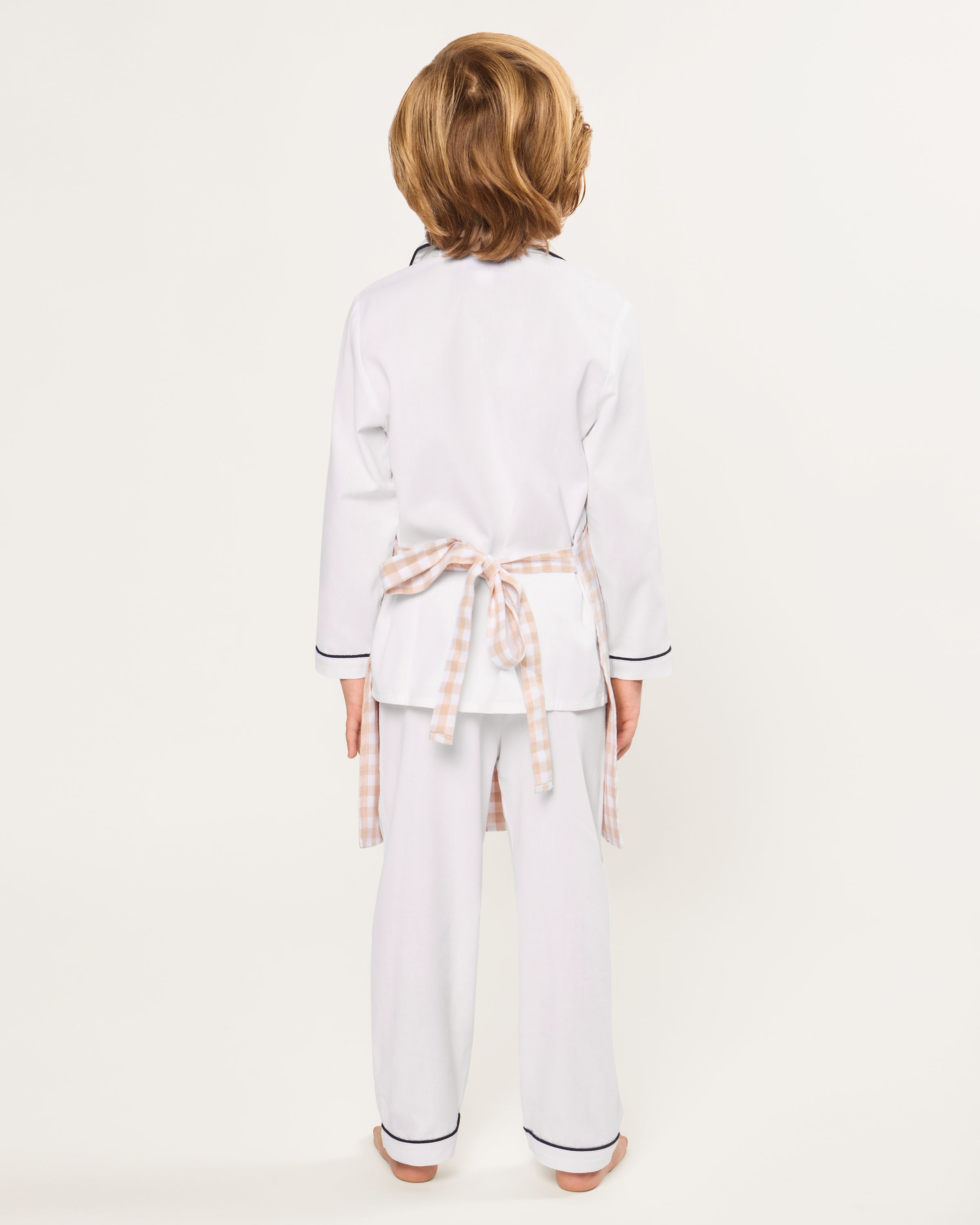 The Kid's Twill Apron in Camel Gingham, featuring a beige and white gingham pattern, two front pockets, and long waist ties, is displayed on a white background.