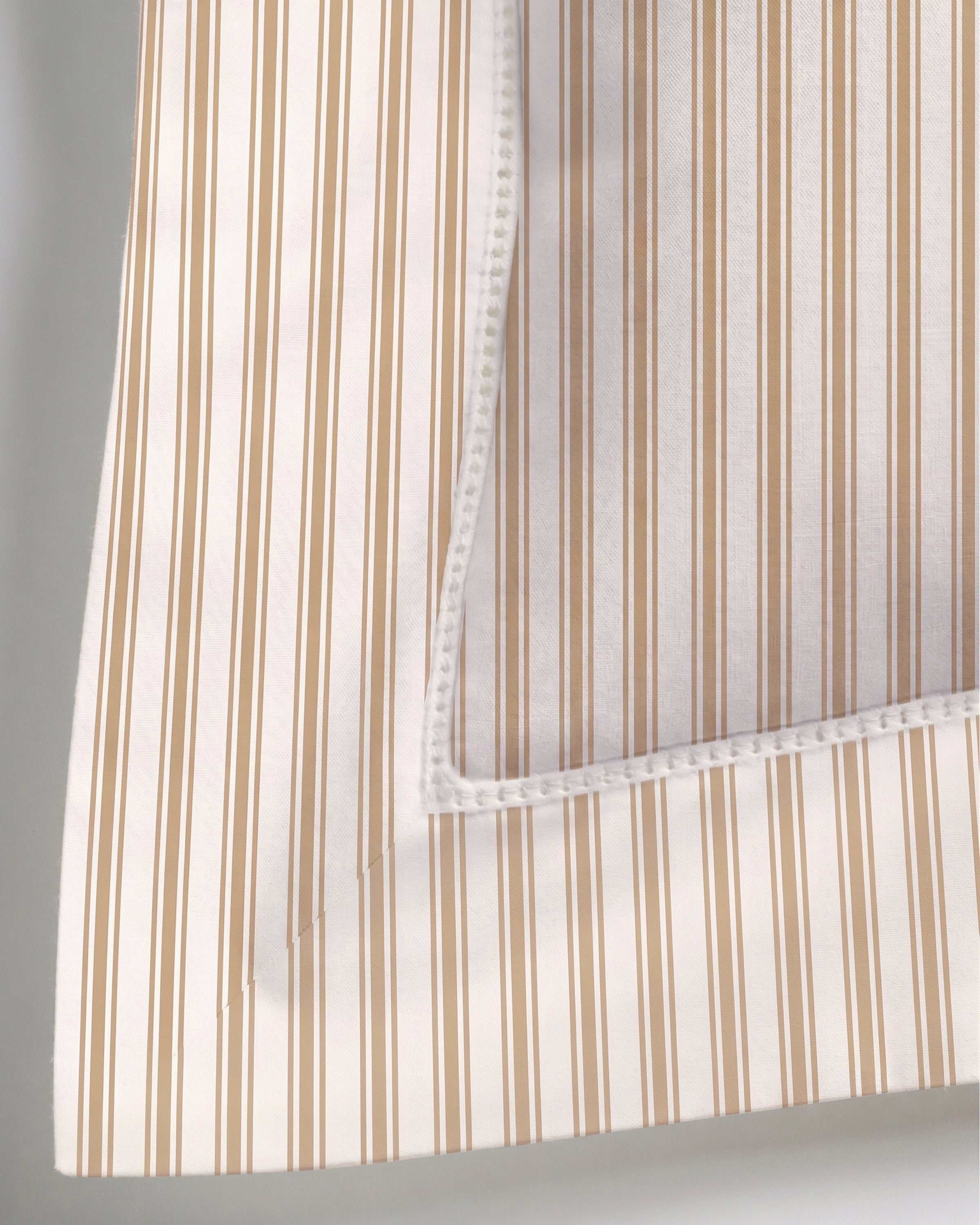 Close-up of a corner of the Luxe Premium Percale Decorative Pillow in Camel Ticking Stripe, featuring vertical beige and white stripes. The corner is folded over to display the neatly stitched edges and the underside of the fabric.
