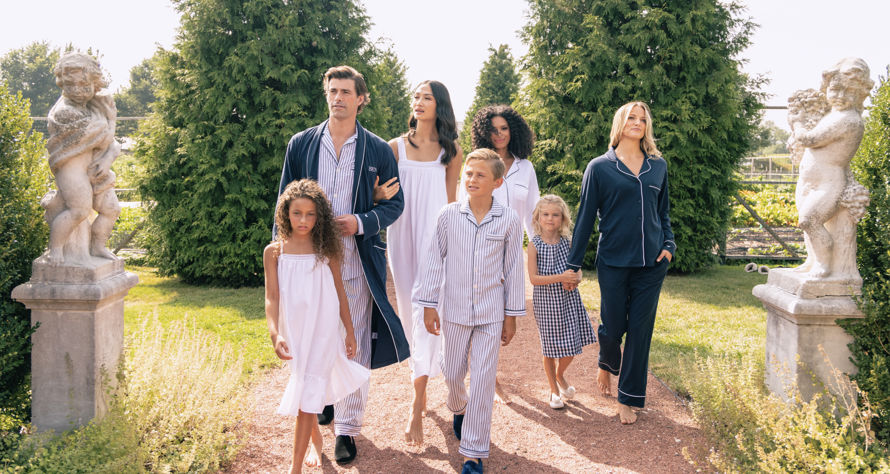 Group of people outside in Navy and white pajamas walking down a gravel path