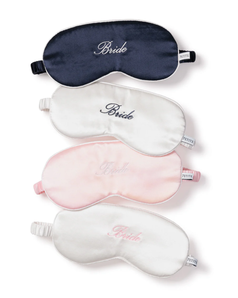 Four premium sleep masks are arranged vertically: dark blue, white, light pink, and off-white. Each pure silk mask from Petite Plume features Bride elegantly embroidered on the front.
