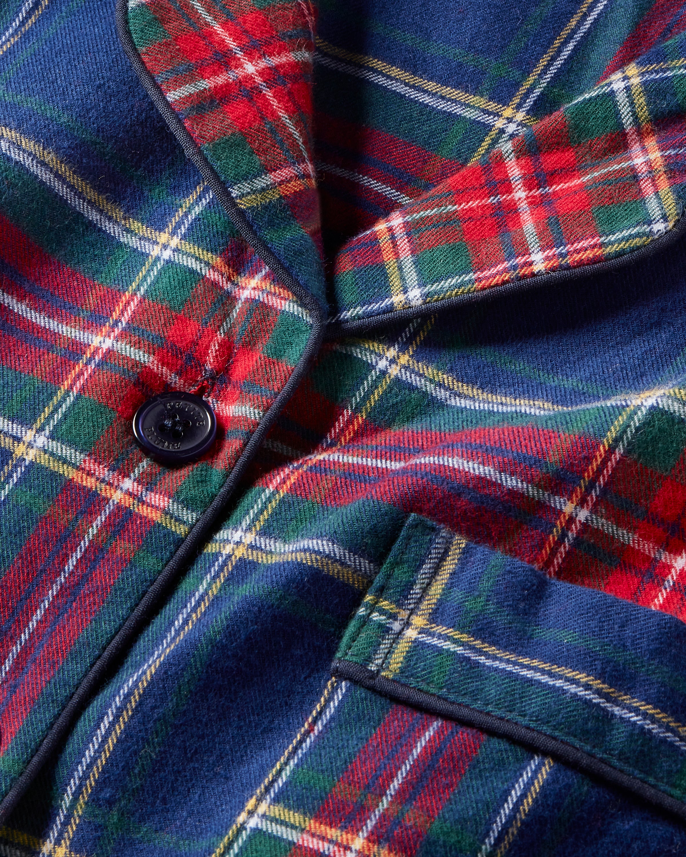 Close-up of a Womens Brushed Cotton Maternity Nightshirt in Windsor Tartan by Petite Plume, showcasing the red, blue, and green plaid with thin yellow and white lines. The image highlights a black button and a pocket with black trim on this luxurious piece.