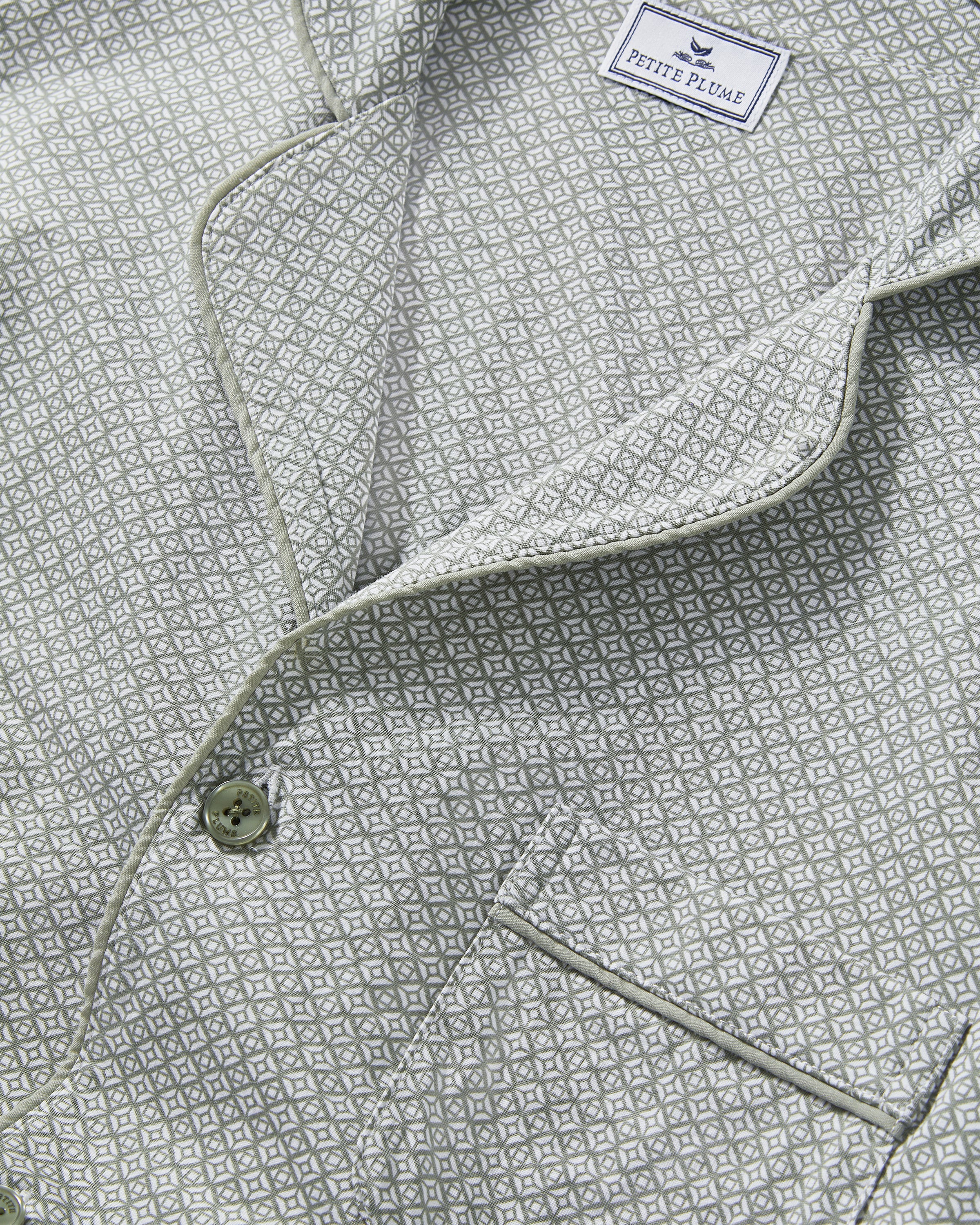 A man with short gray hair and light stubble stands barefoot in the Men's Lightweight Pima Pajama Set in Sage Geo against a white background, gazing to the side with a relaxed expression.