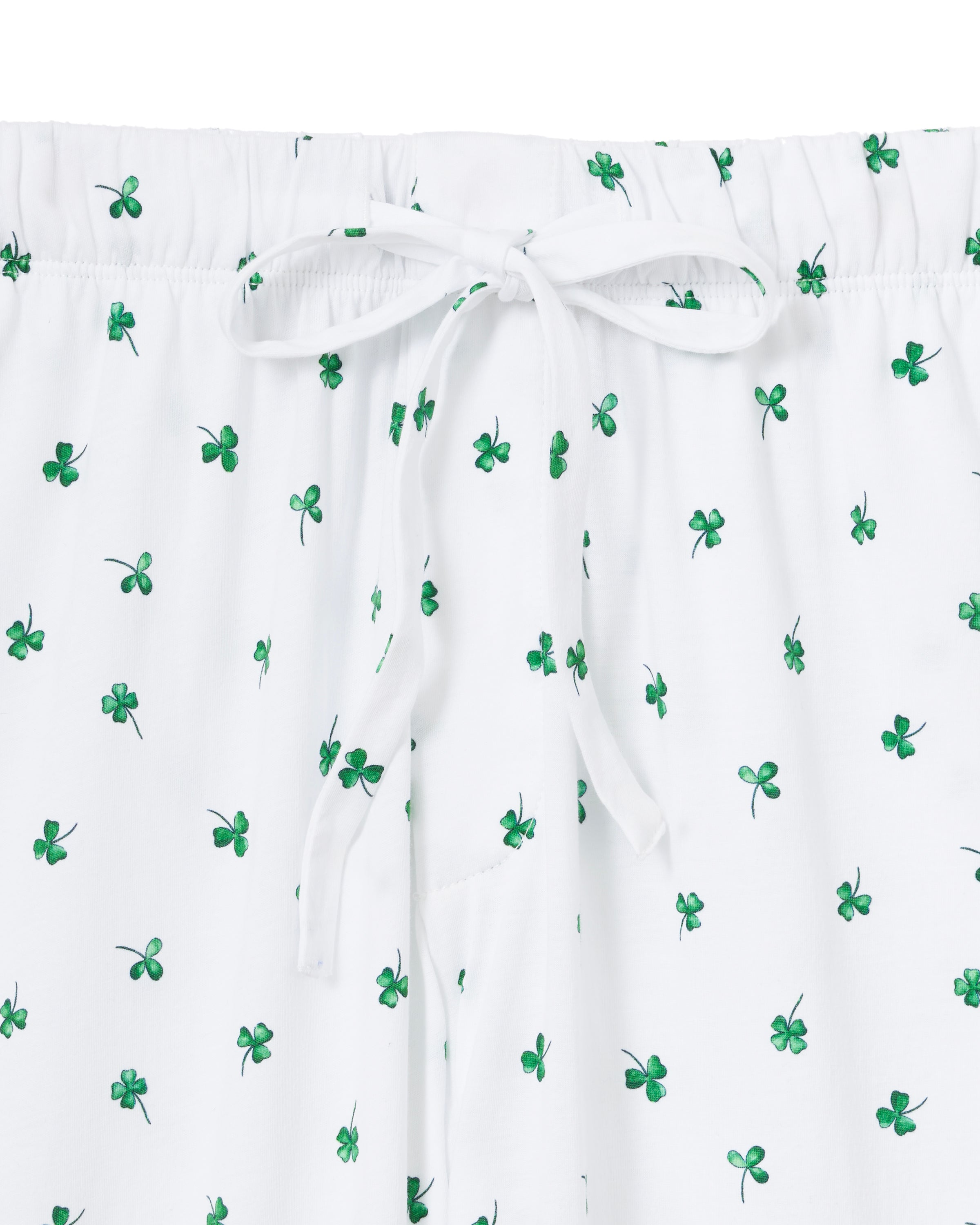 A man with short gray hair stands barefoot against a plain light background, wearing a plain white tee and Men's Pima Pants in Shamrocks—a white pajama pant with a small green pattern.
