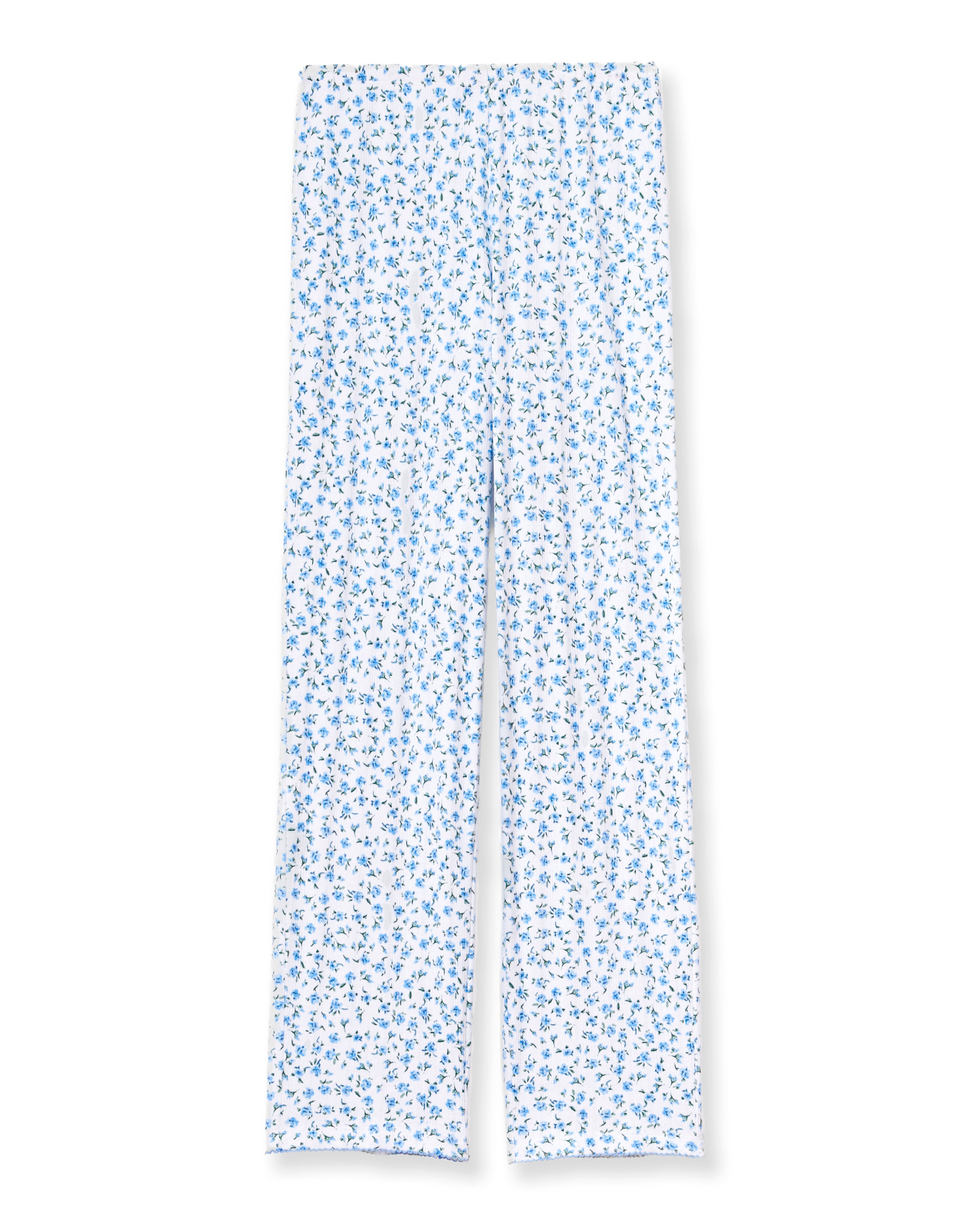 A woman stands barefoot against a plain background, wearing the Women's Pointelle Pant in Blue Floral paired with a matching short-sleeve pajama top featuring a white base and small blue floral print.