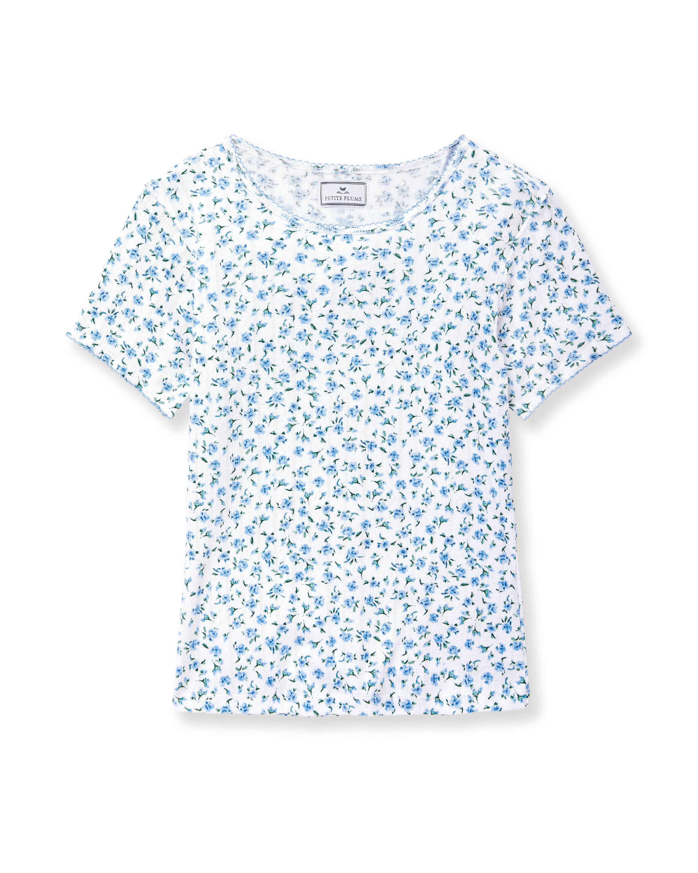 A young woman with long curly brown hair wears the Women's Pointelle T-Shirt in Blue Floral, paired with a matching skirt, against a plain light background.