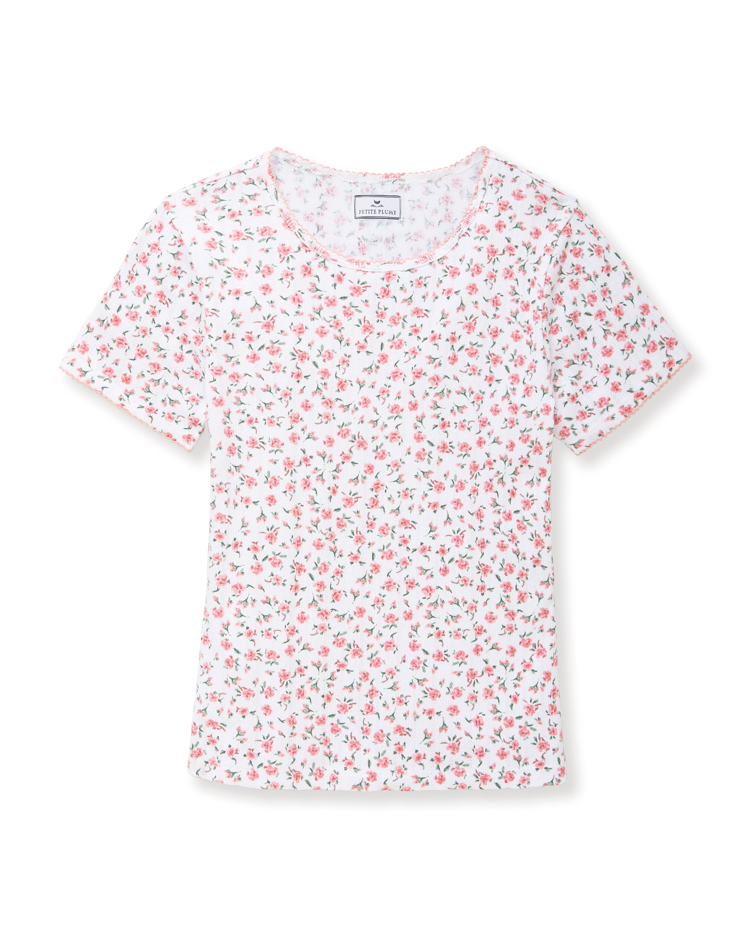 A woman with long curly hair wears the Women's Pointelle T-Shirt in Pink Floral, standing against a plain light background.