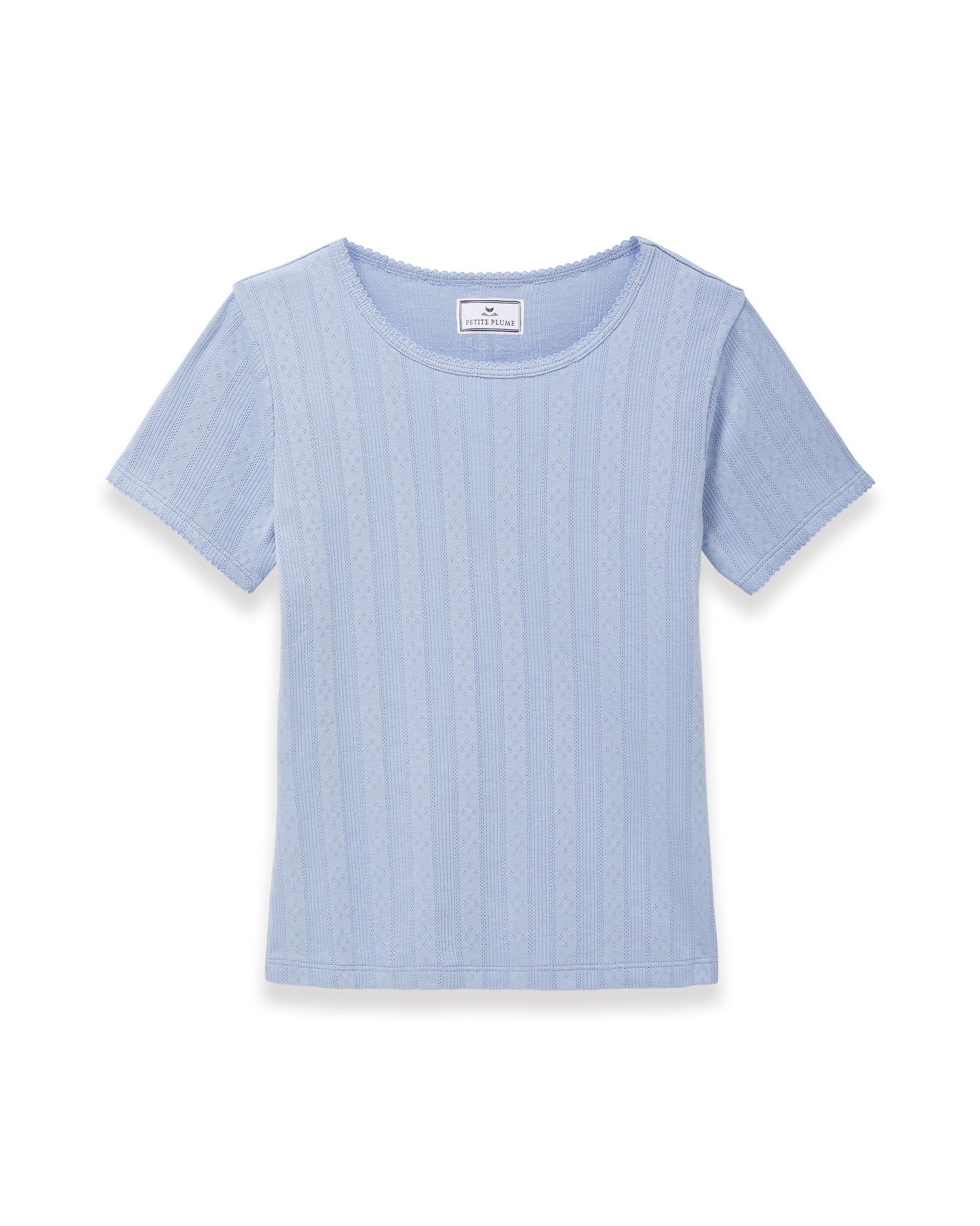 A woman with long wavy hair wears the Women's Pointelle T-Shirt in Periwinkle and matching pants, standing against a plain light background and looking at the camera with a slight smile.