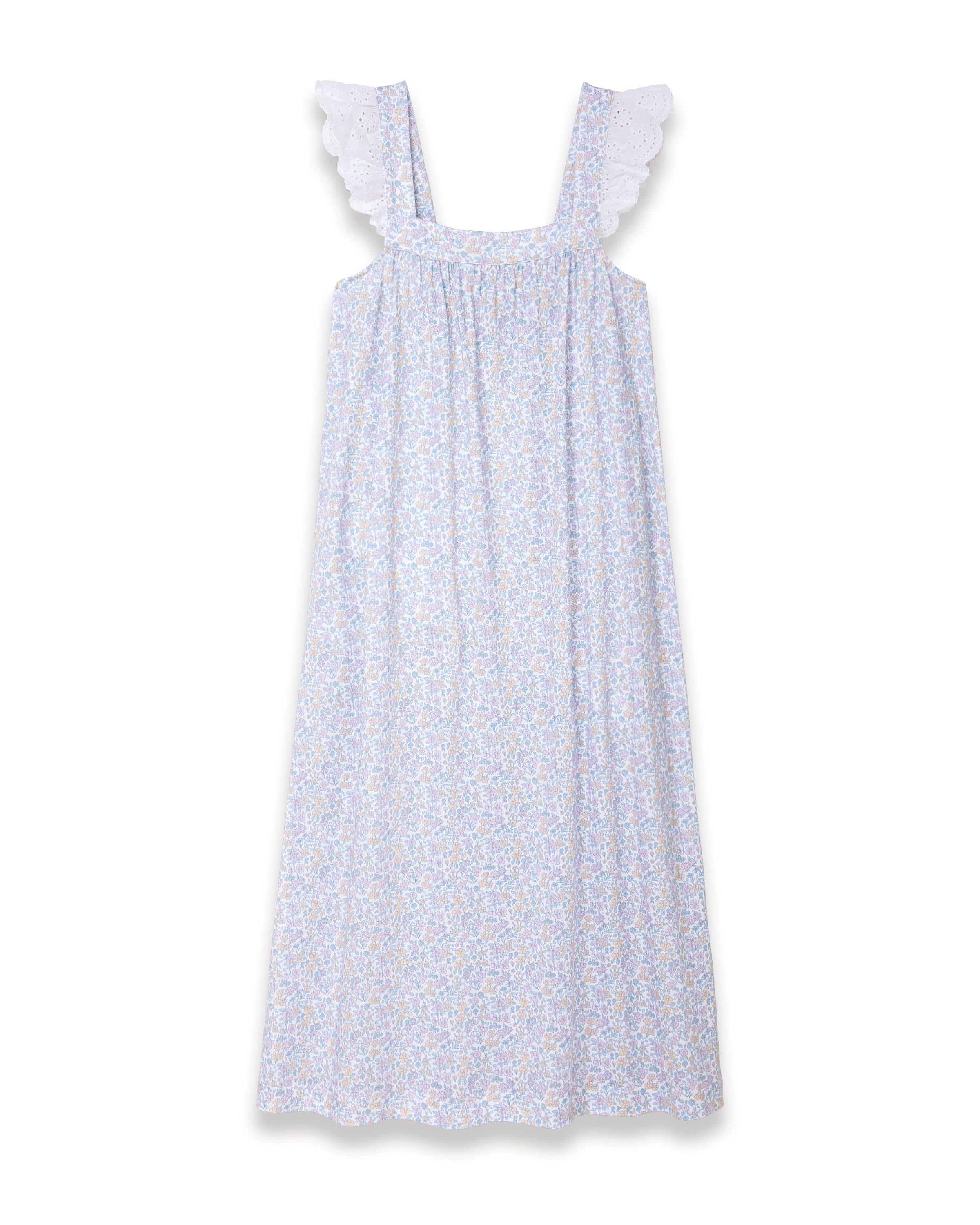 A woman with long curly hair stands barefoot on a plain light background, wearing the Women's Lightweight Pima Clara Nightgown in Fleur Blanche—an ankle-length, sleeveless gown with dainty floral print and lace-trimmed straps.