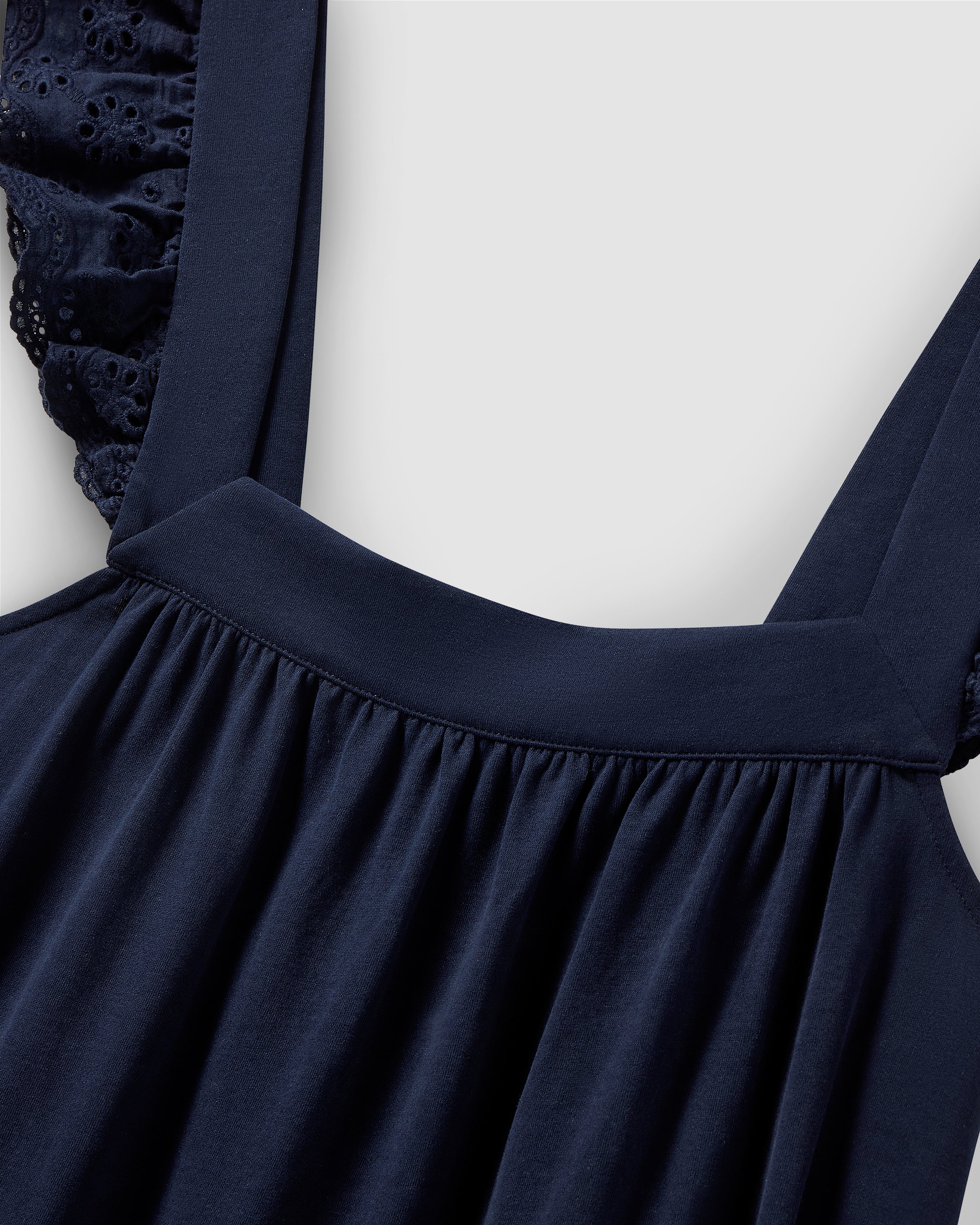 Close-up of Petite Plumes Womens Pima Clara Nightgown in Navy, showcasing wide straps and a square neckline made from soft jersey knit. Gathered texture and eyelet lace sleeve details are highlighted against a plain light grey background.