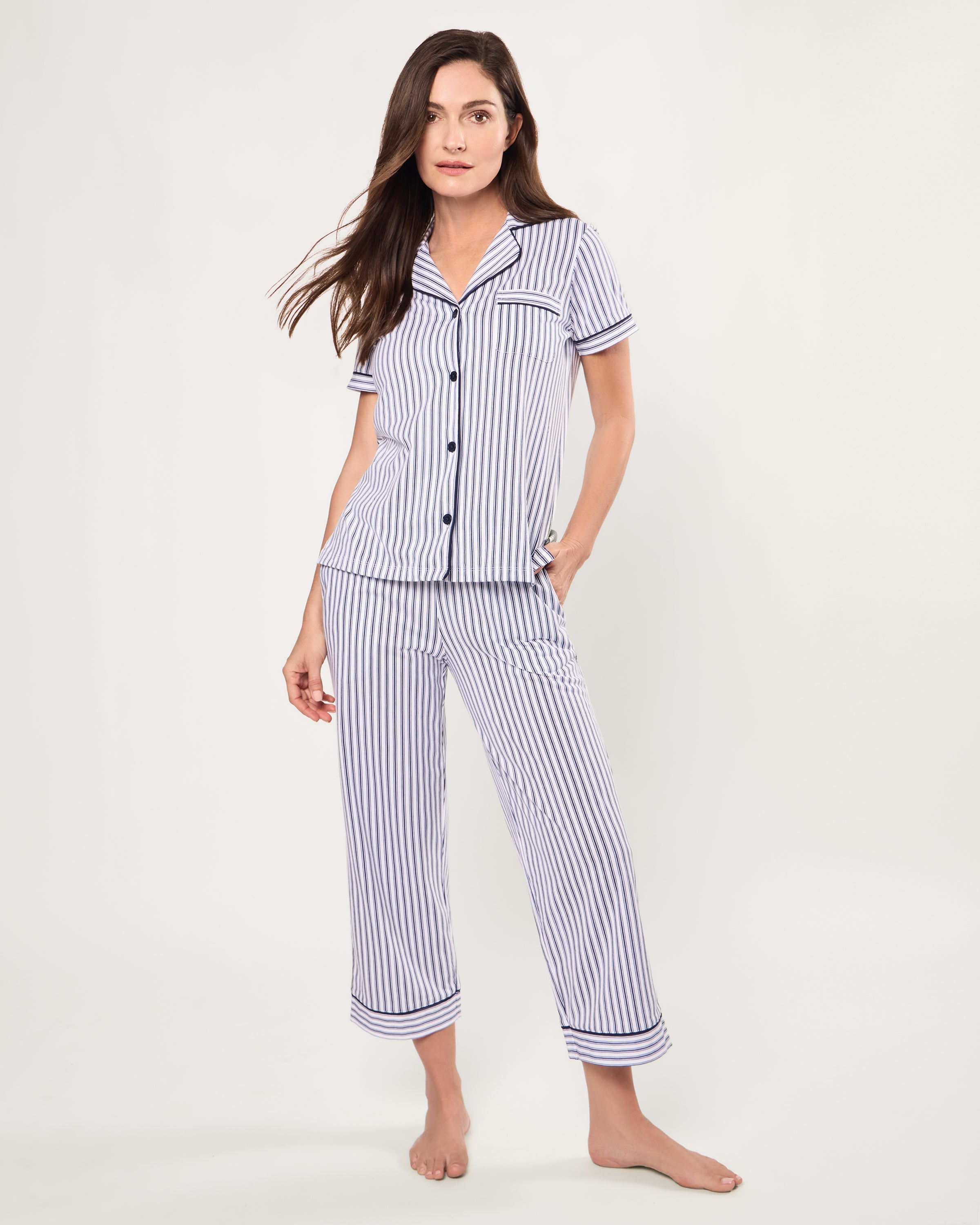 The Women's Pima Crop Pajama Set in Navy French Ticking features a blue and white vertical stripe design, short sleeves, a collared button-up top with chest pocket, and matching long pants.