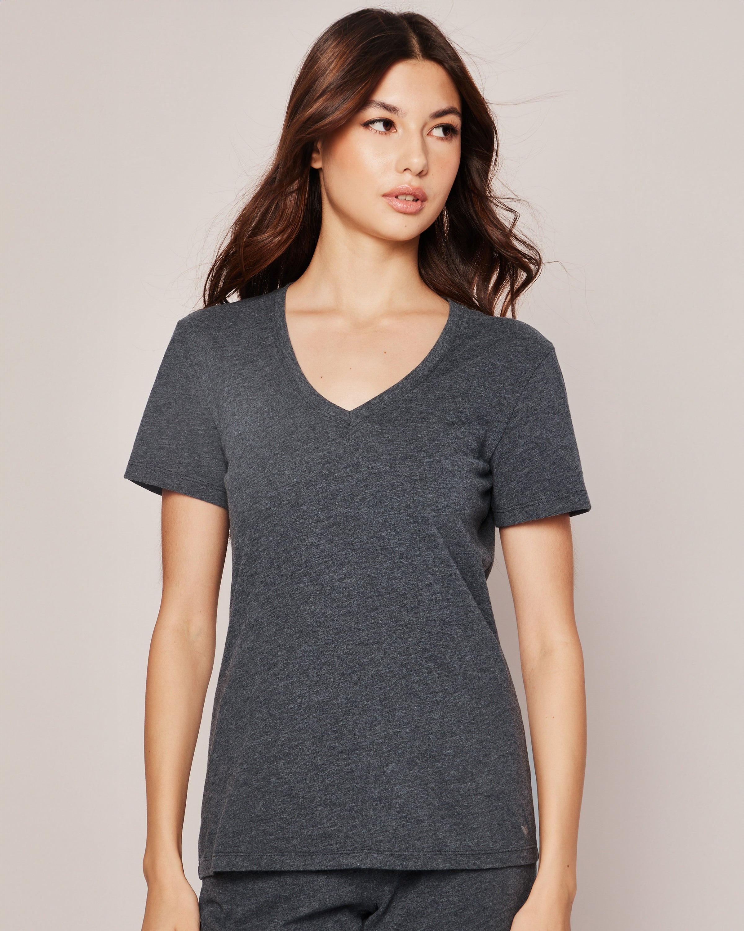 A person with long, dark hair in a Petite Plume Womens Pima Short Sleeve Top in Dark Heather Grey looks to the side against a neutral background, highlighting the elegance of breathable Peruvian Pima cotton fabric.