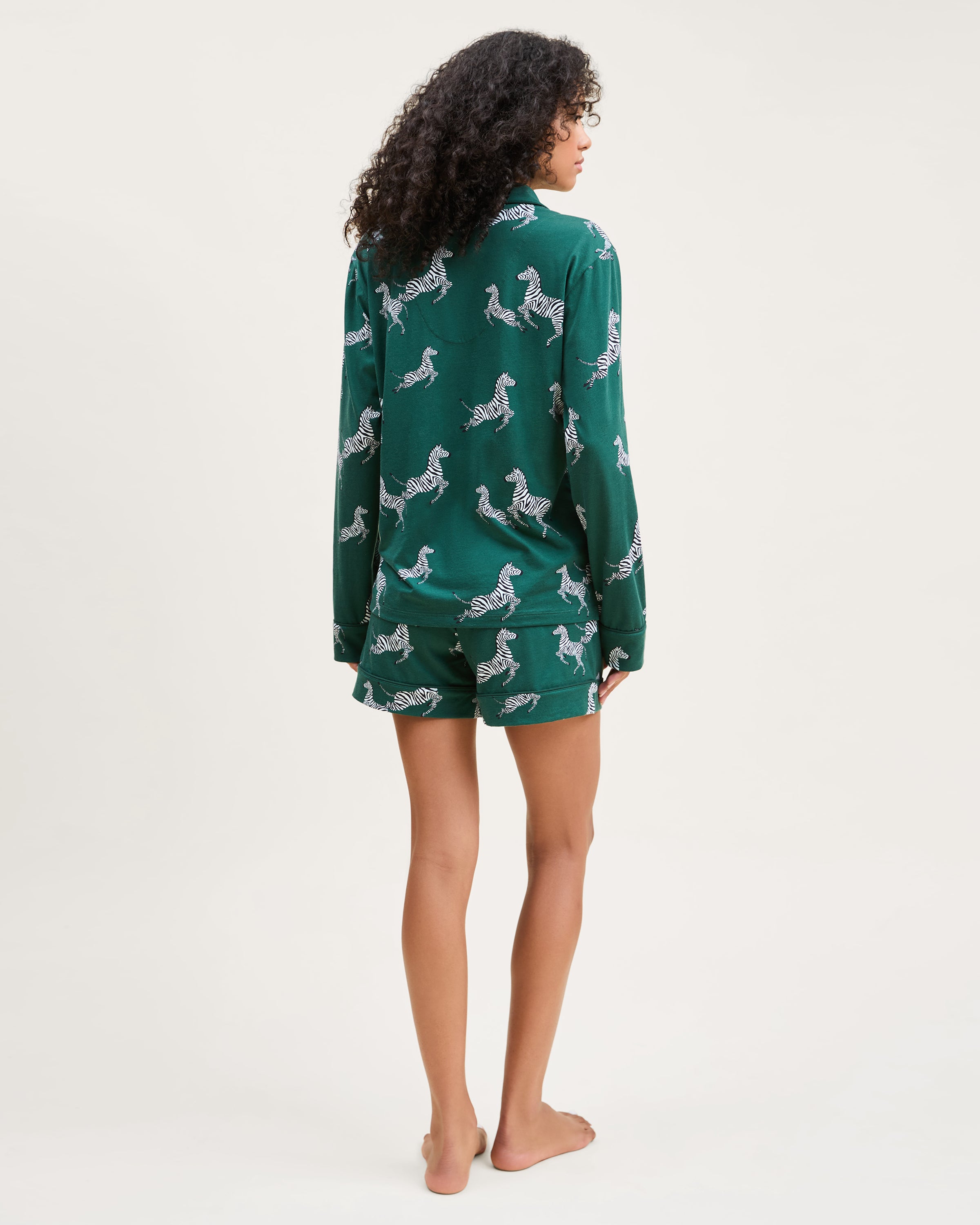The Women's Pima Long Sleeve Short Set in Zèbre de Forêt features a green button-up shirt and matching shorts, both adorned with an allover playful white zebra print.