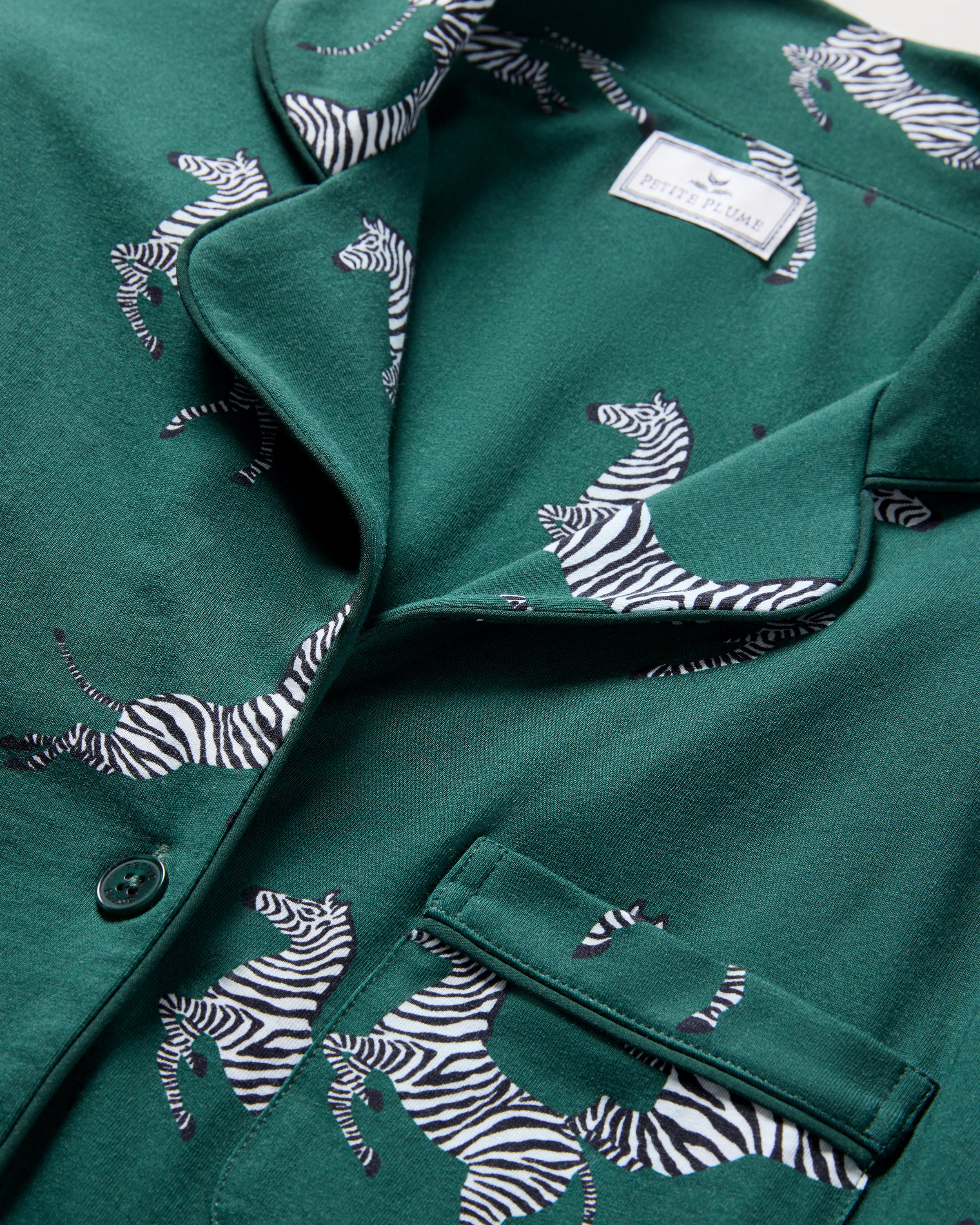 The Women's Pima Long Sleeve Short Set in Zèbre de Forêt features a green button-up shirt and matching shorts, both adorned with an allover playful white zebra print.