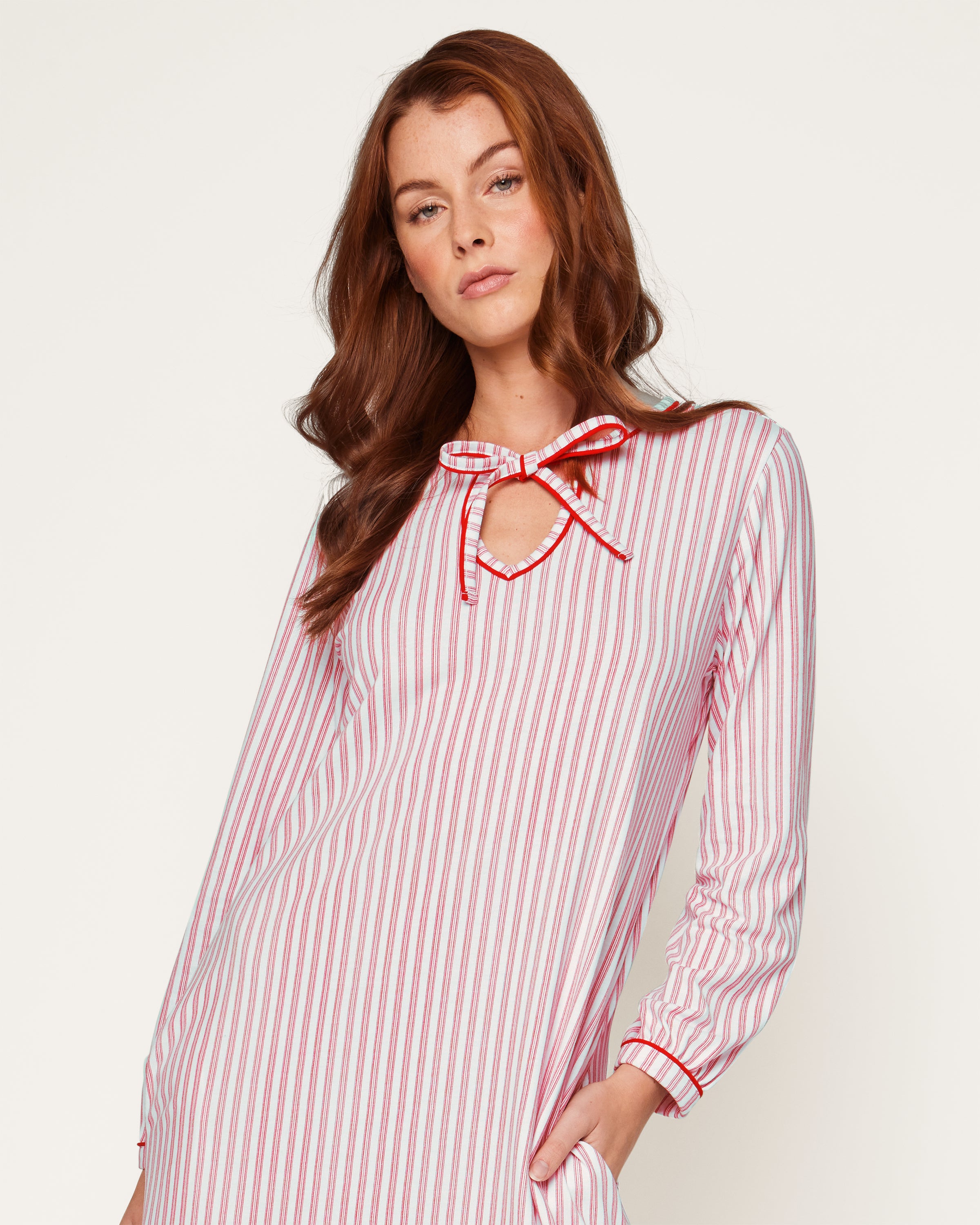 A close-up of the Womens Pima Harlow Nightgown in Antique Red Ticking showcases a red and white striped pattern, made from premium Peruvian Pima cotton. It features a keyhole neckline tied with matching fabric laces, with the Petite Plume label visible on top.