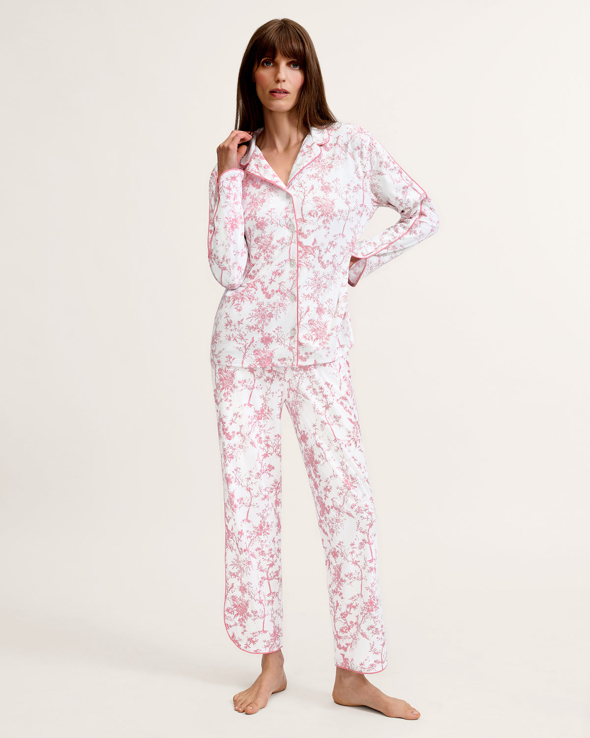 The Margaux Pima Pajama Set in Pink Timeless Toile features long sleeves, soft white fabric with a pink floral toile pattern, and pink piping along the edges and collar.