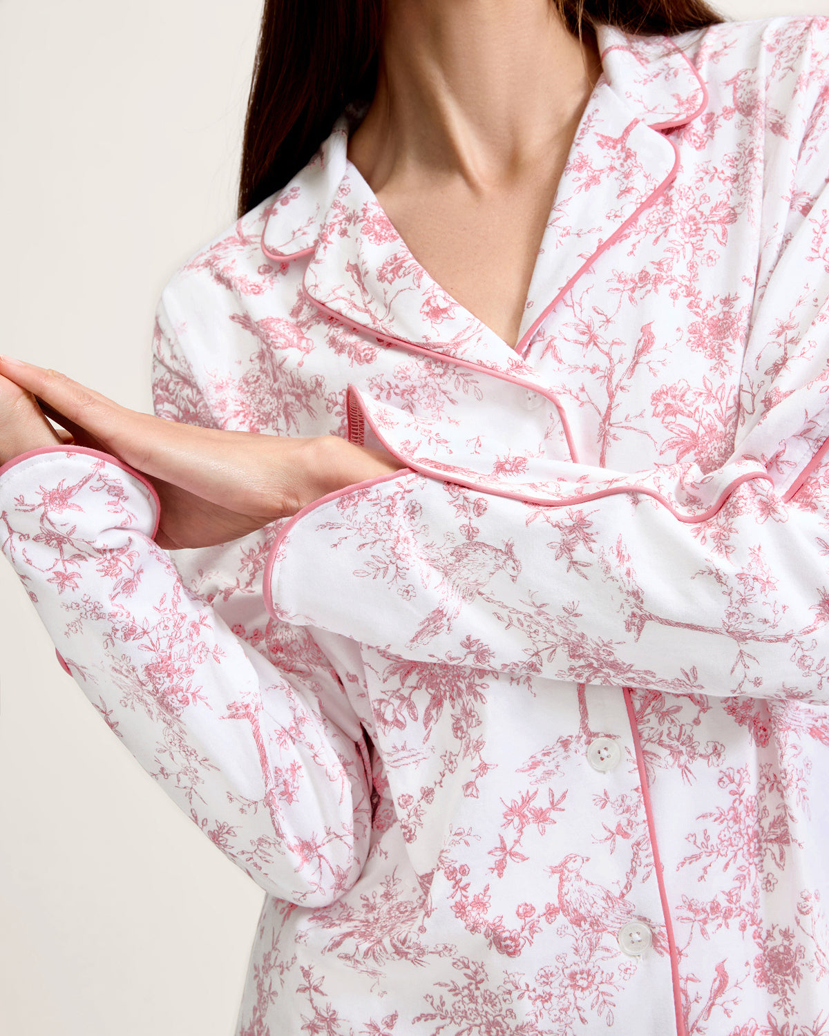 The Margaux Pima Pajama Set in Pink Timeless Toile features long sleeves, soft white fabric with a pink floral toile pattern, and pink piping along the edges and collar.