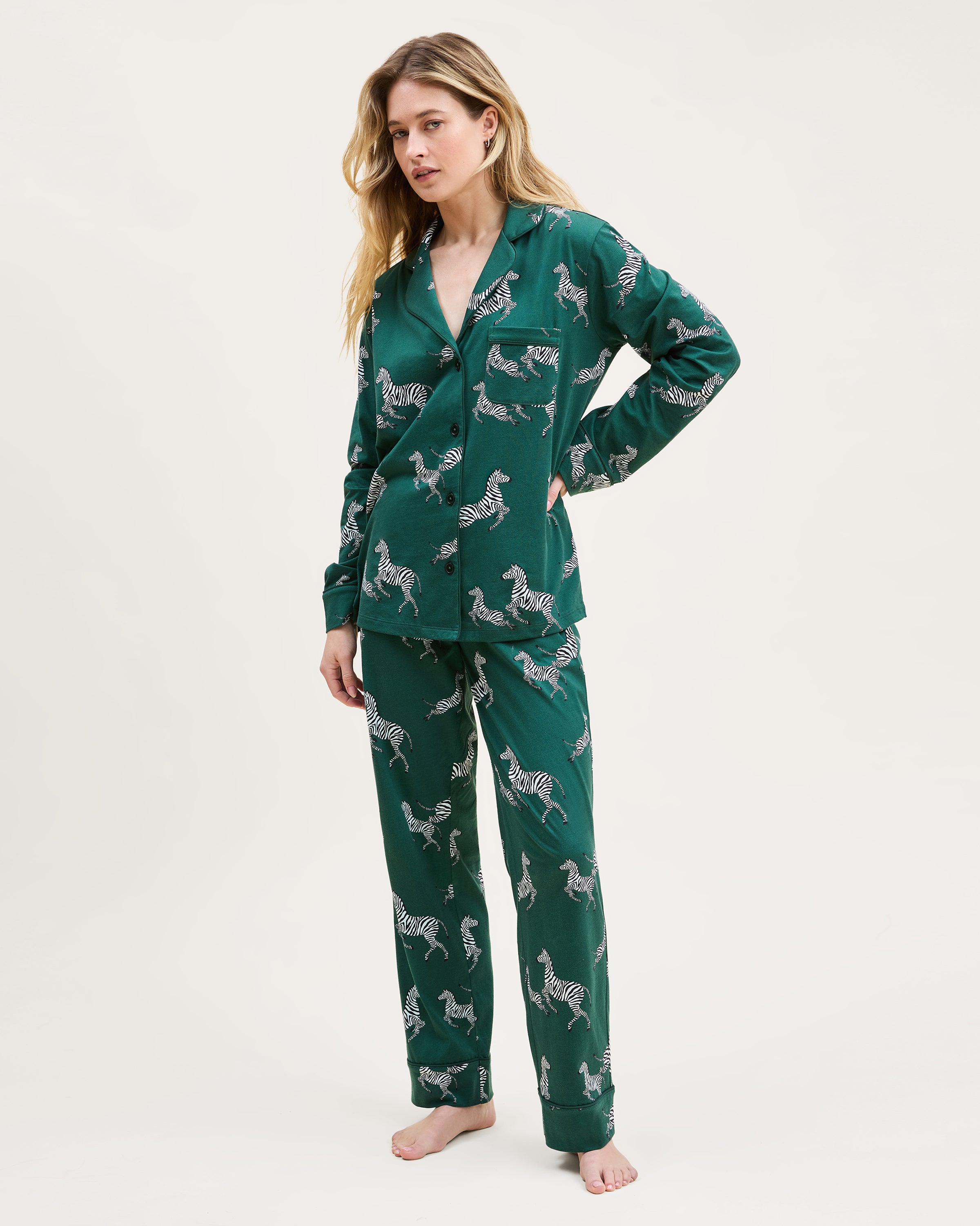 Women's Pima Pajama Set in Zèbre de Forêt: dark green set with button-up long-sleeve shirt and pants, featuring an all-over white zebra print, chest pocket, and collar.