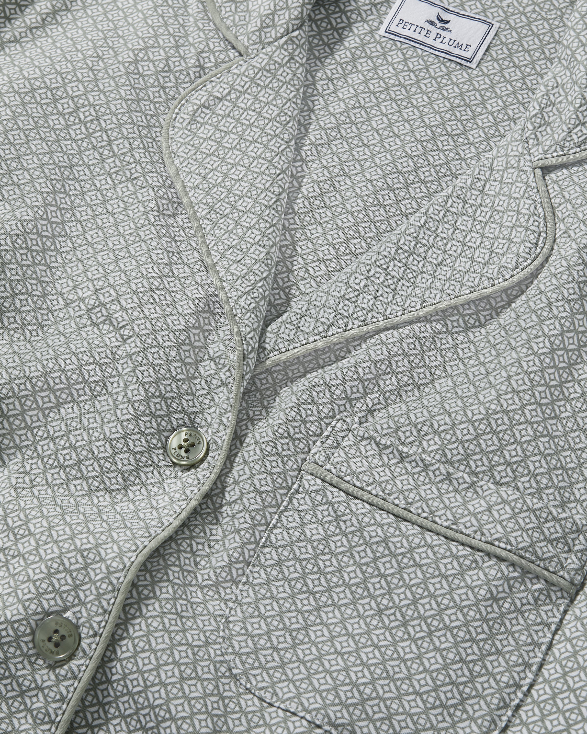 A woman stands barefoot in the Women's Lightweight Pima Short Sleeve Short Set in Sage Geo—featuring a button-up shirt and matching shorts with a small geometric pattern—against a plain light background.