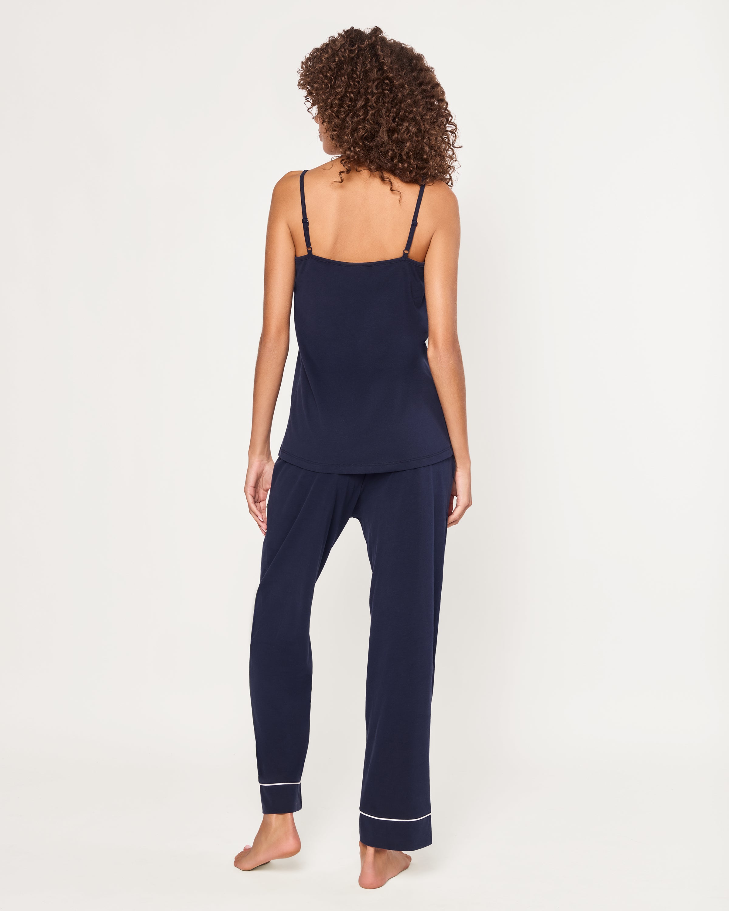 The Women's Pima Sylvie Pajama Set in Navy includes a sleeveless V-neck camisole with thin straps and matching long pants, both featuring white trim. The set is displayed flat on a white background.