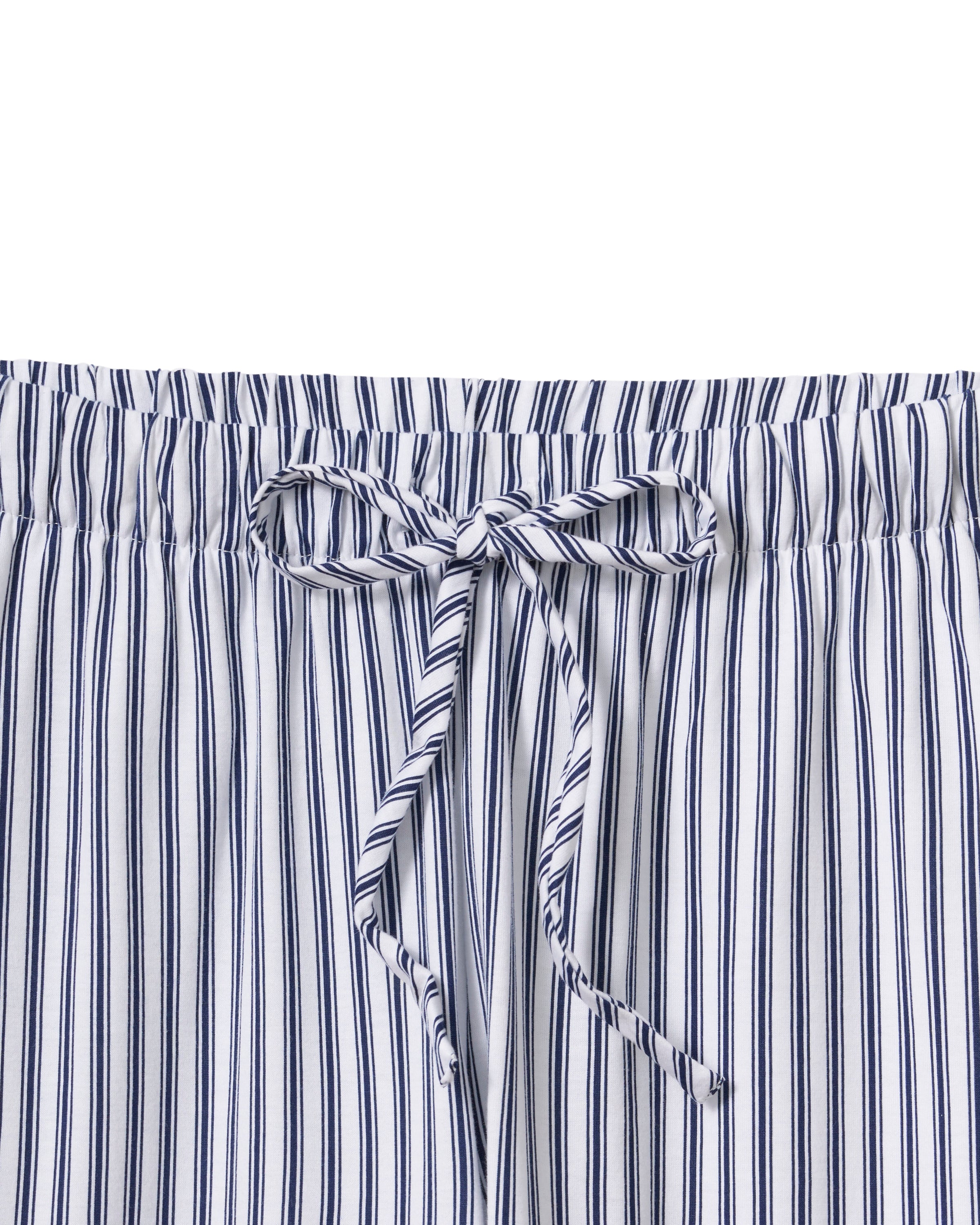 A person with long dark hair is wearing Petite Plumes Olivia Wide Leg Pima Pajama Set in Navy French Ticking, crafted from luxurious Peruvian Pima cotton. The button-up shirt and wide-legged pants have vertical stripes in alternating dark and light colors. They stand barefoot against a plain background.