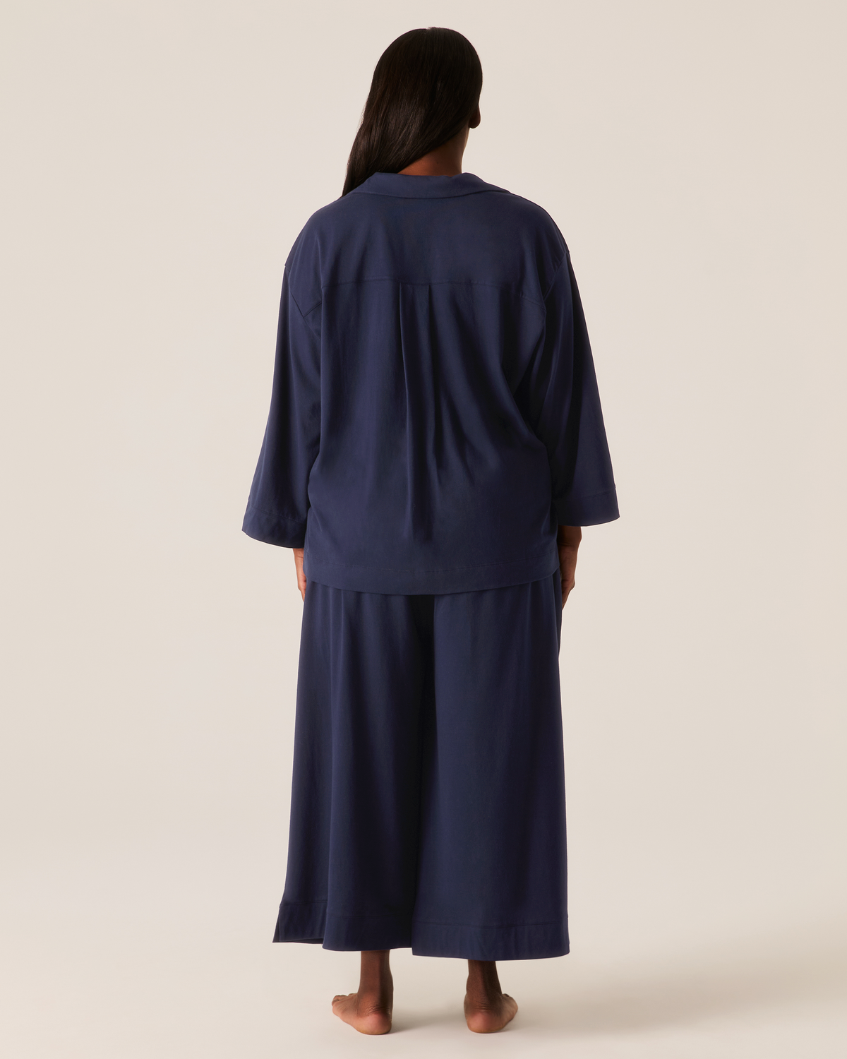 Back view of a person wearing The Olivia Wide Leg Pima Pajama Set in Navy, featuring a button-down top and wide-leg trousers.