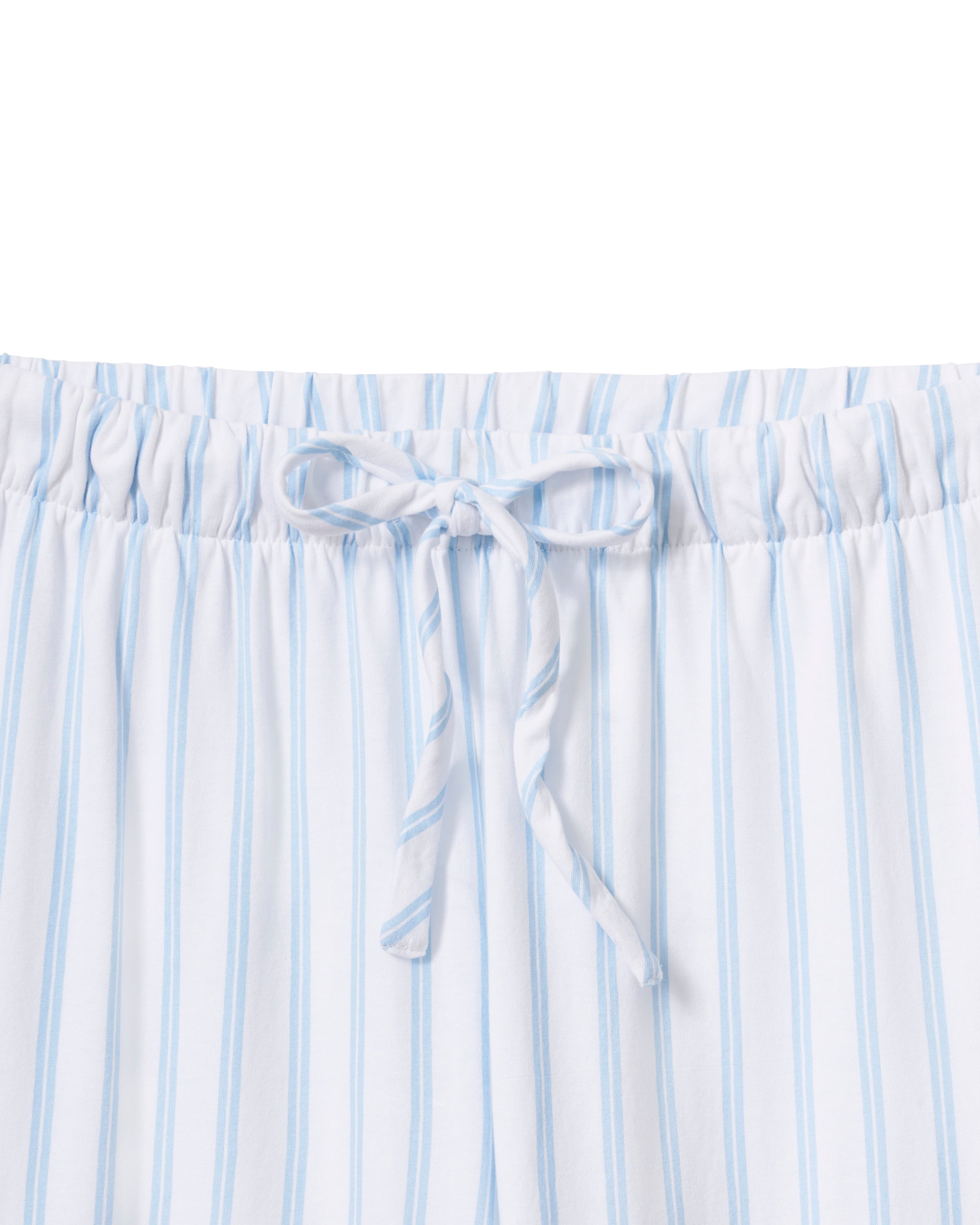 A person models the Petite Plumes Olivia Wide Leg Pima Pajama Set in Periwinkle Stripe, featuring a soft, luxurious white and light blue striped button-up long-sleeve shirt with matching wide-leg pants against a plain background that enhances its elegant simplicity.