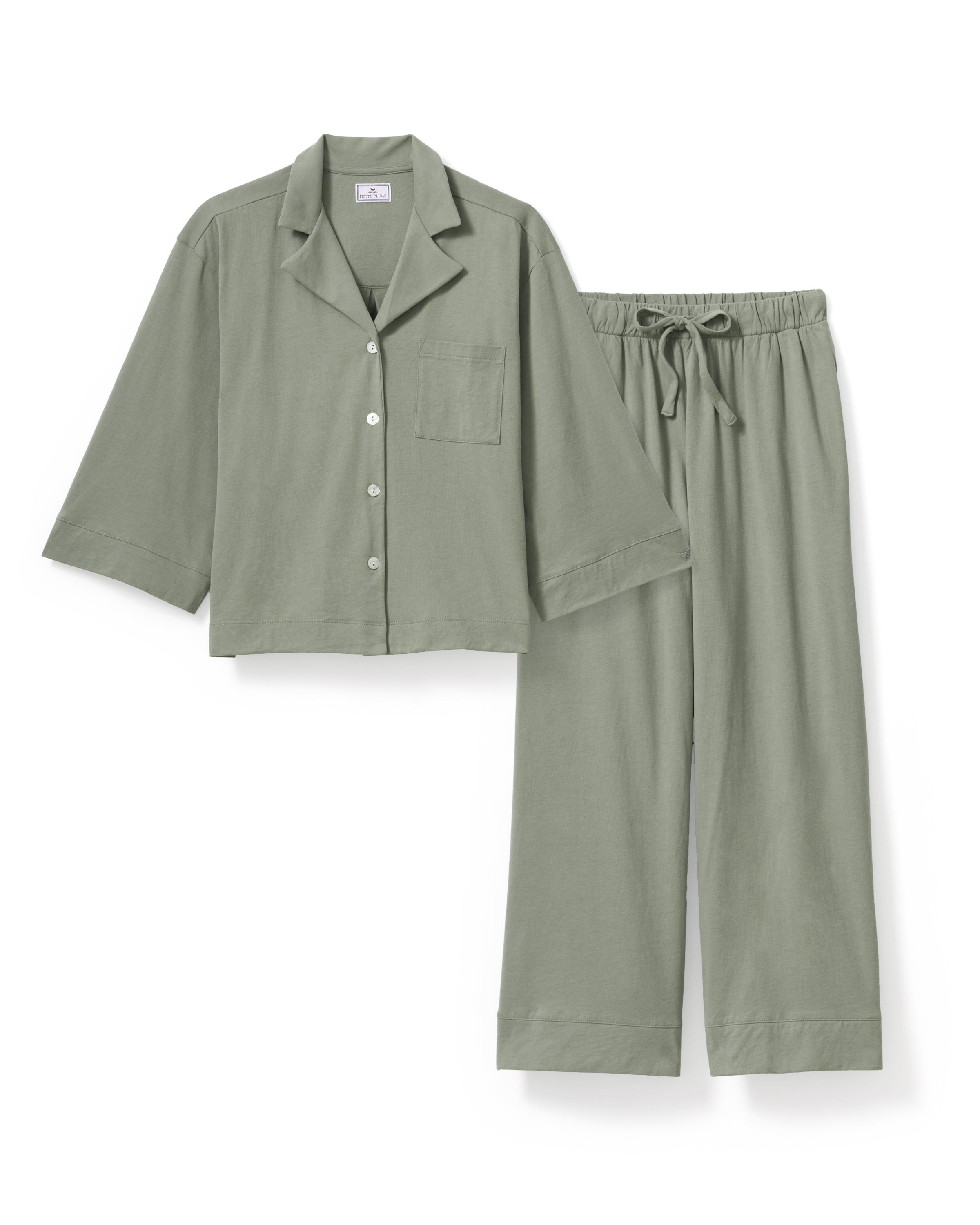 The Olivia Wide Leg Pima Pajama Set in Sage includes a button-up, collared top with a chest pocket and three-quarter sleeves, plus matching elastic waist wide-leg pants. Both pieces are neatly laid flat on a white background.