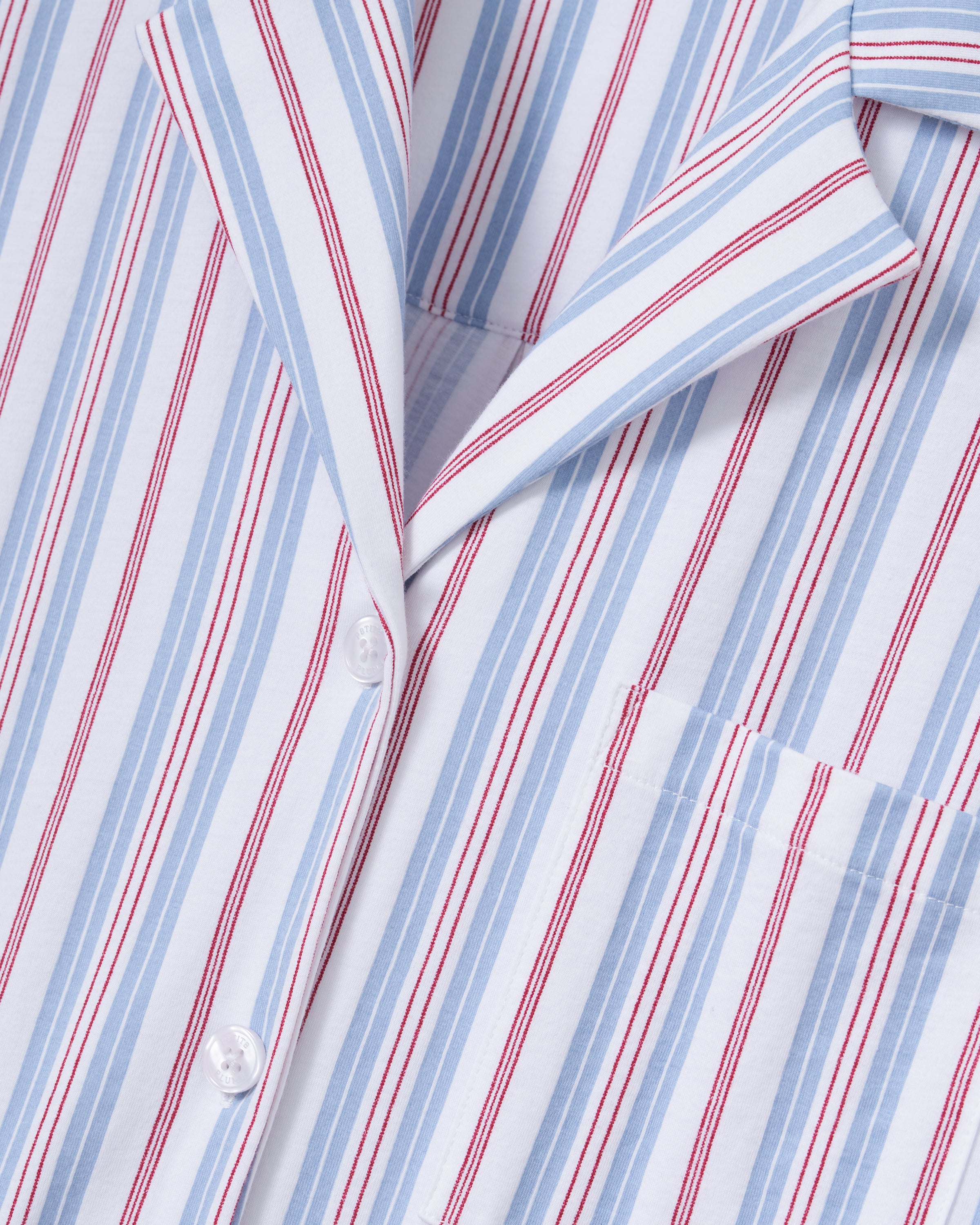 Close-up of The Olivia Wide Leg Lightweight Pima Pajama Set in Vintage French Stripes, featuring blue and red vertical stripes, white buttons, a collared design, and a chest pocket.