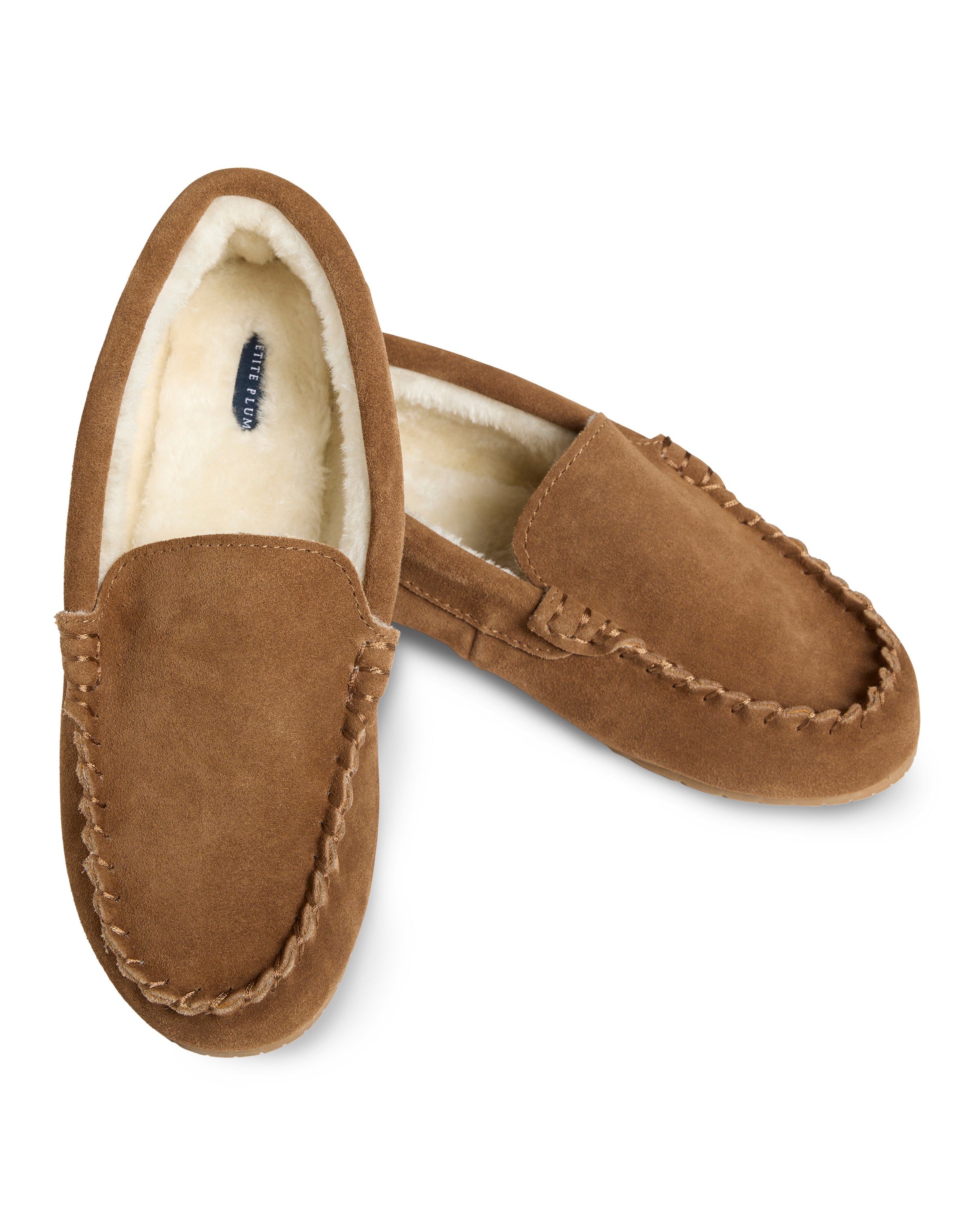 Petite Plumes Mens Suede Slippers in Tan feature intricate stitching and an ultra-soft faux fur lining, with one slipper angled atop the other to display its luxurious interior.