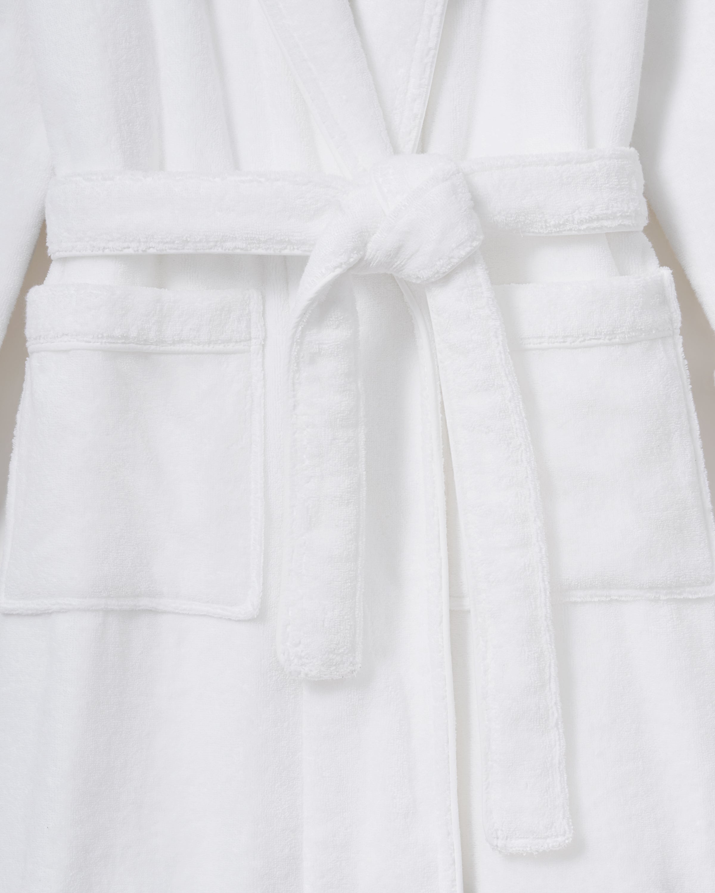 The Unisex Luxe Terry Robe in White features long sleeves, a shawl collar, two front pockets, and a waist tie belt, displayed against a white background.