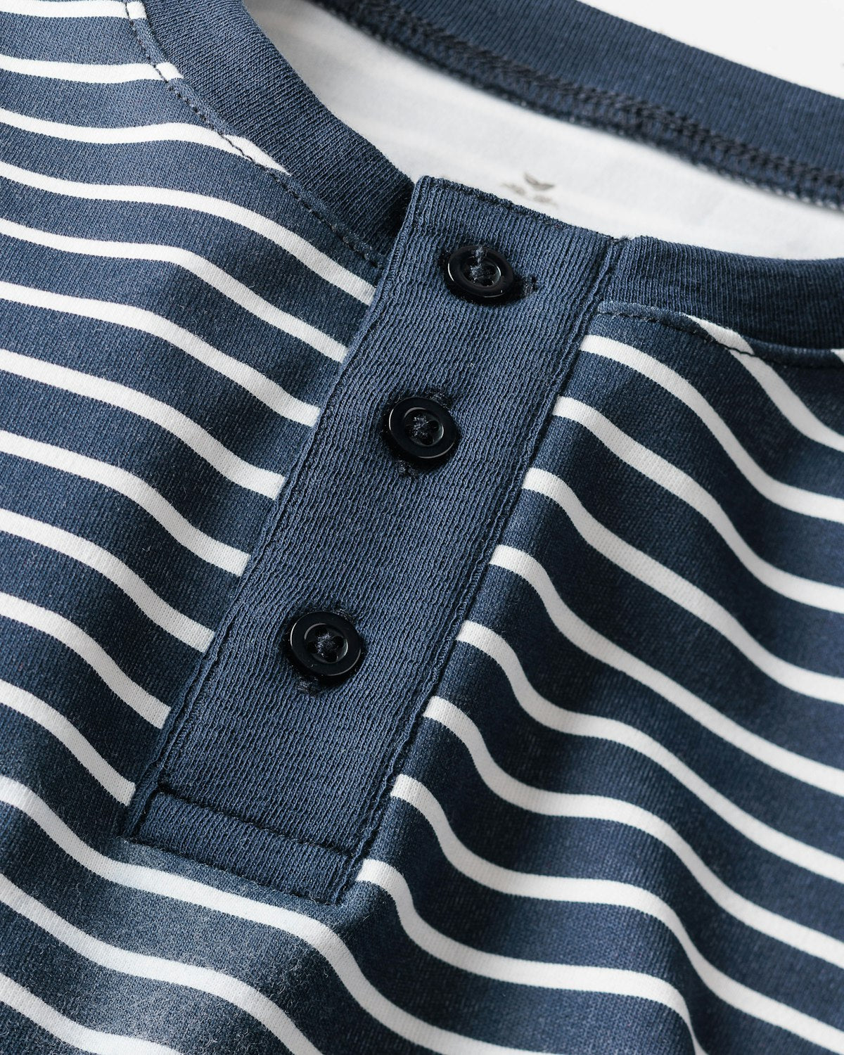 Close-up of the Navy Stripe Kids Pima Snug Fit Pajama Set by Petite Plume. This cozy sleepwear features a navy and white striped Pima cotton henley top with horizontal stripes and a dark blue placket with three black buttons.