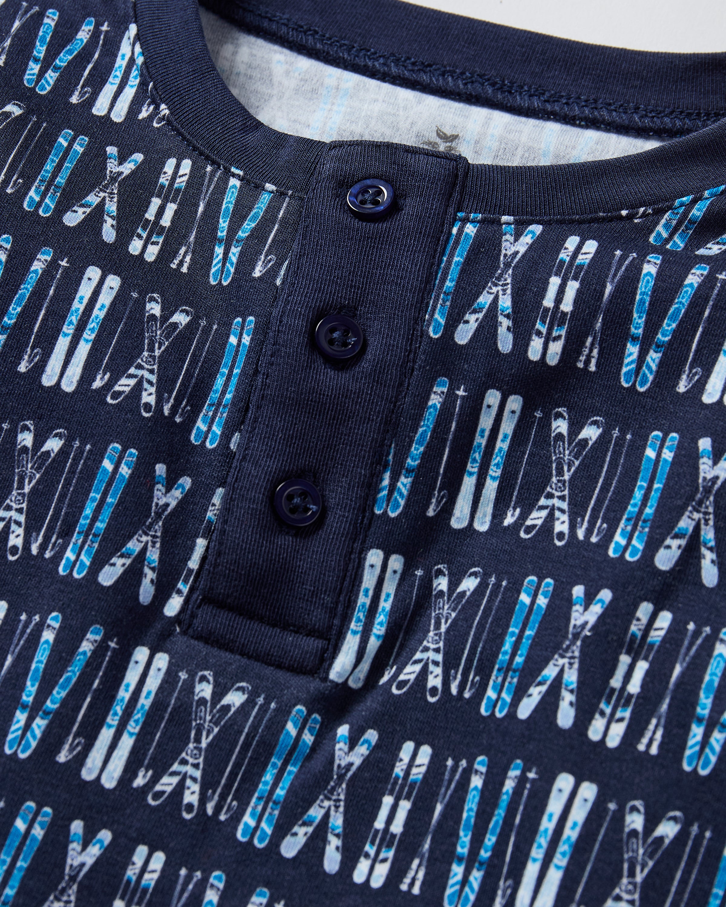 The Kid's Pima Snug Fit Pajama Set in Ski Trails features a coordinated long-sleeve top and pants with a blue and black geometric design and dark blue cuffs on the sleeves, neckline, and pant legs.