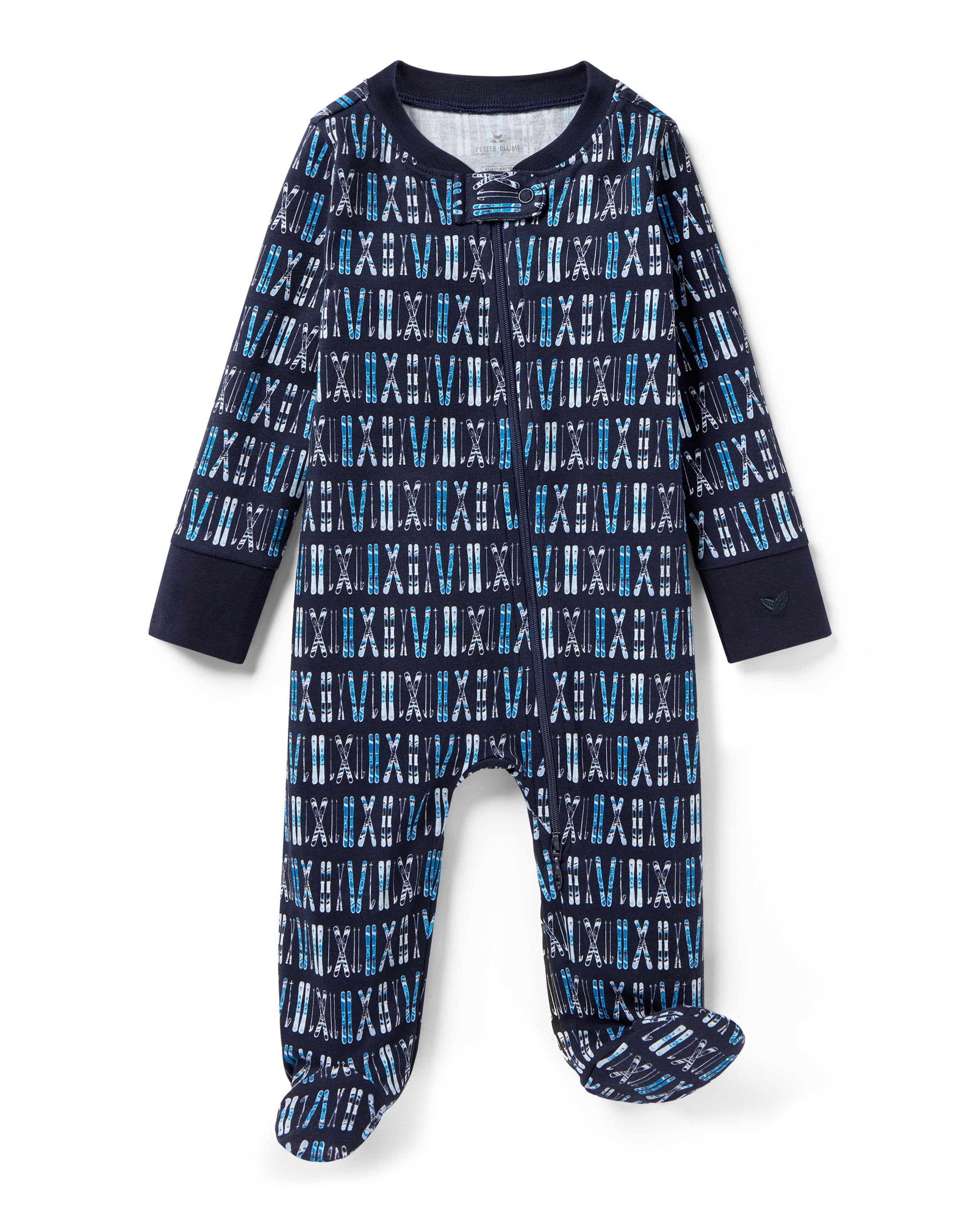 The Baby's Pima Romper in Ski Trails is a navy blue zip-up footed onesie with an all-over pattern of white and blue skis and ski poles arranged vertically.