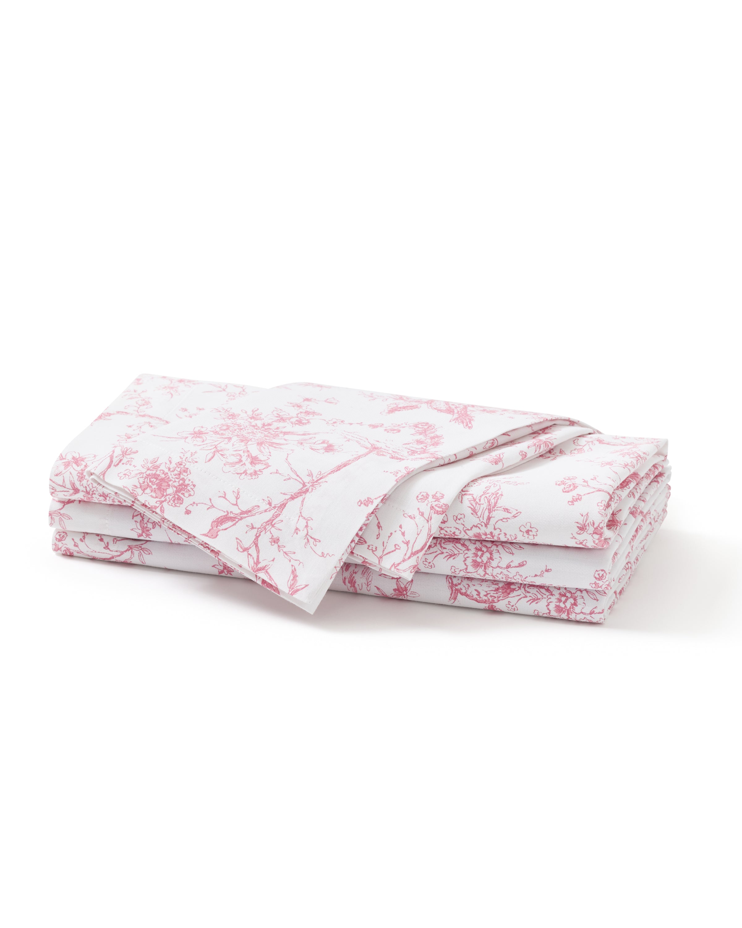 A neatly folded stack of Signature Twill Napkins in Pink Timeless Toile, featuring a delicate pink floral and branch pattern, displayed on a plain white background.