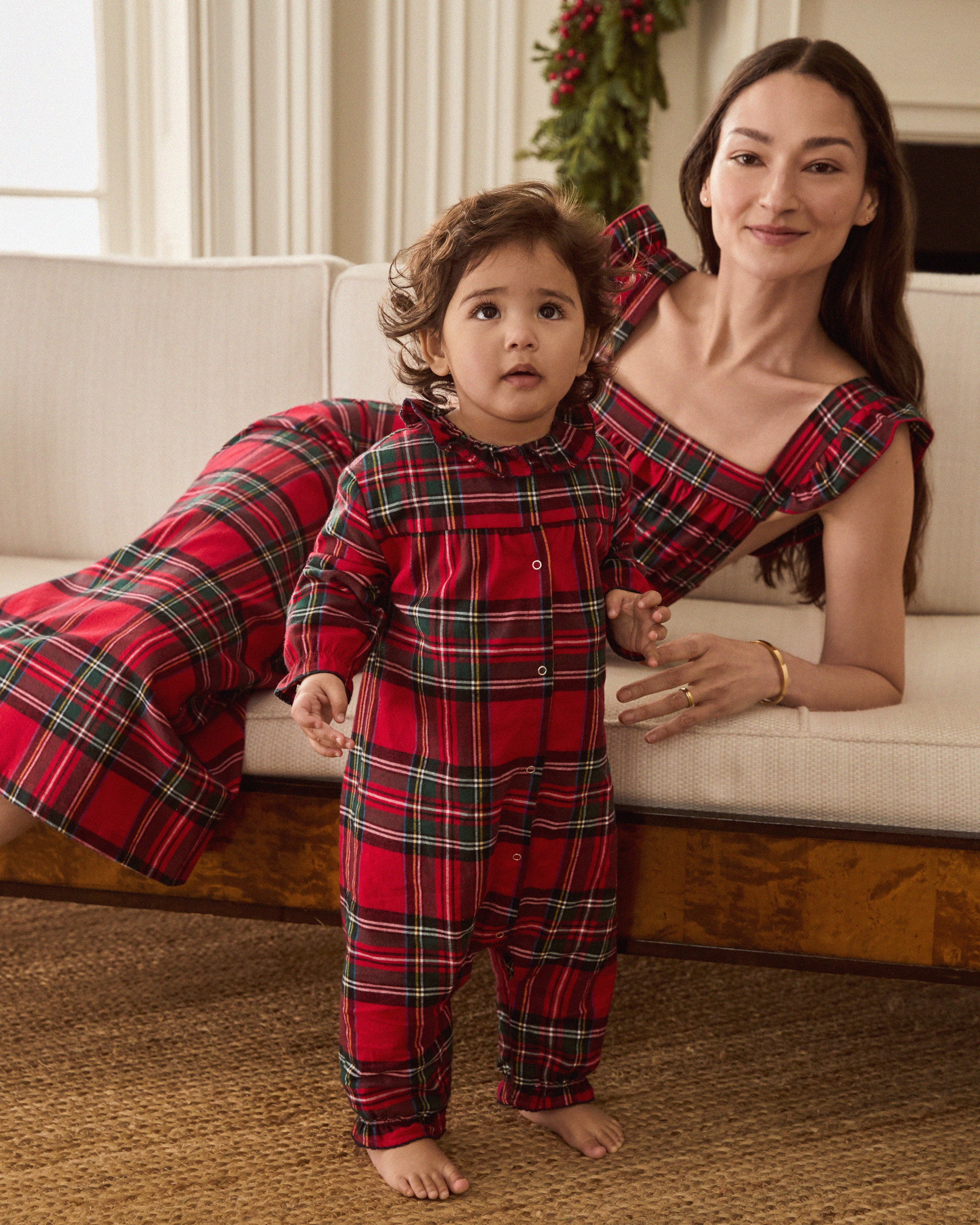 The Baby's Brushed Twill Madeline Romper in Imperial Tartan features long sleeves, a ruffled collar, snap buttons down the front, and gathered cuffs, all in a festive red, green, and white plaid.