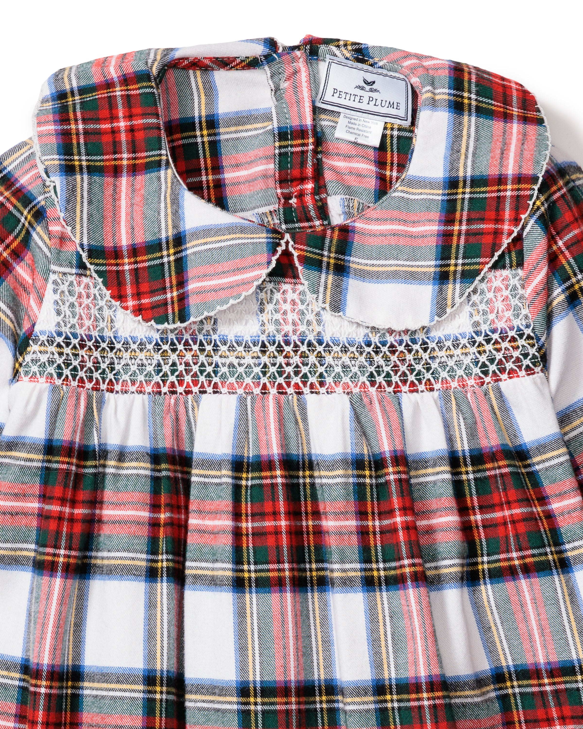 A close-up of Petite Plumes Girls Brushed Cotton Eloise Nightgown in Balmoral Tartan, featuring a red, blue, and white plaid pattern. It highlights a rounded collar and intricate smocking below the neckline, exuding classic charm.
