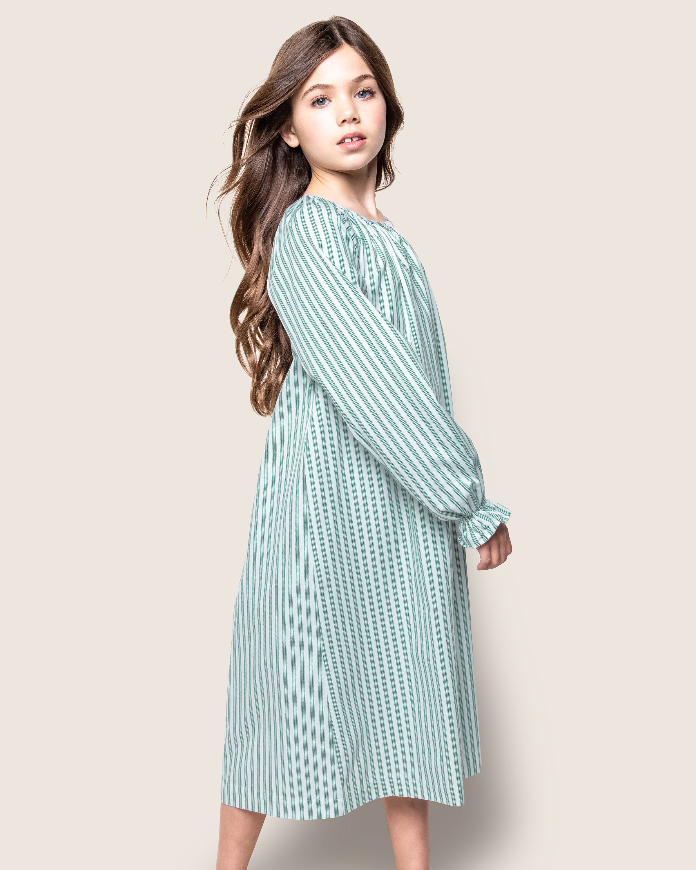 The Girl's Twill Delphine Nightgown in Emerald Ticking features vertical green and white stripes, long sleeves with ruffled cuffs, a gathered neckline, and a small bow detail at the center.