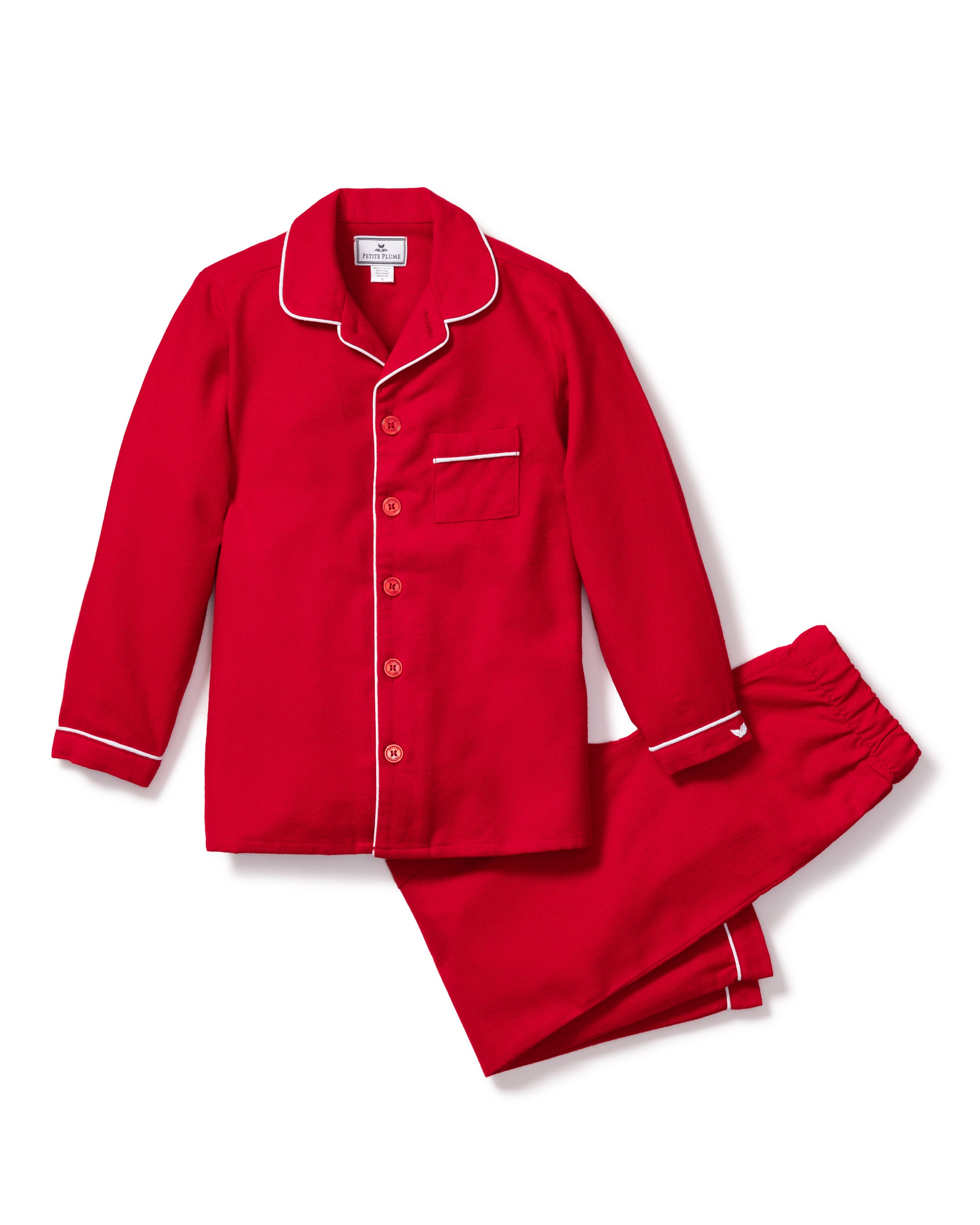 The Petite Plume Kids Flannel Pajama Set in Red, featuring a long-sleeve button-up top with white piping, a pocket, and matching pants, is displayed on a white background.