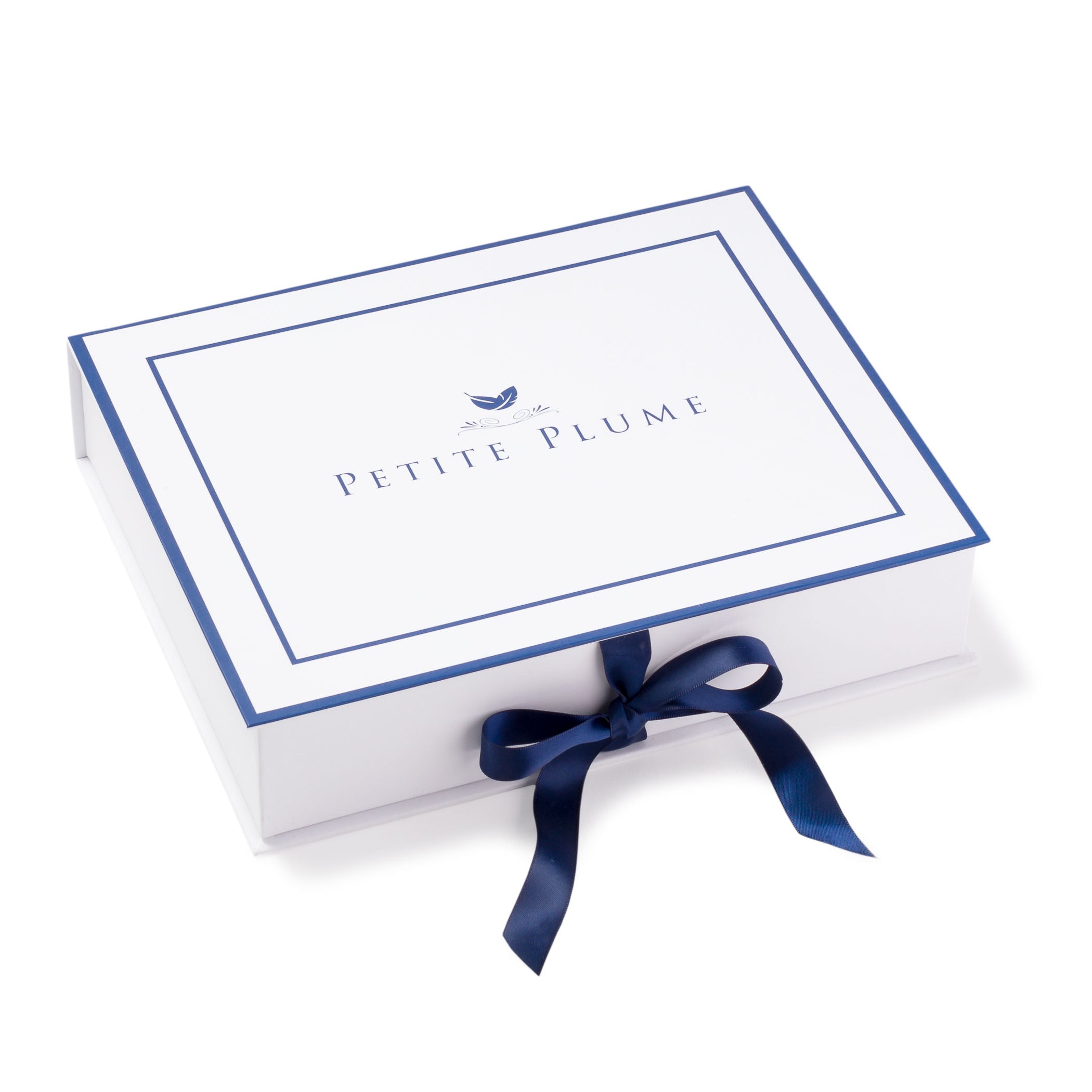 A white gift box with a blue border and a stylized feather logo with Petite Plume text in the center is tied with a blue ribbon bow, ideal for presenting Womens Juliette Ballet Slipper in Navy Velvet by Petite Plume.