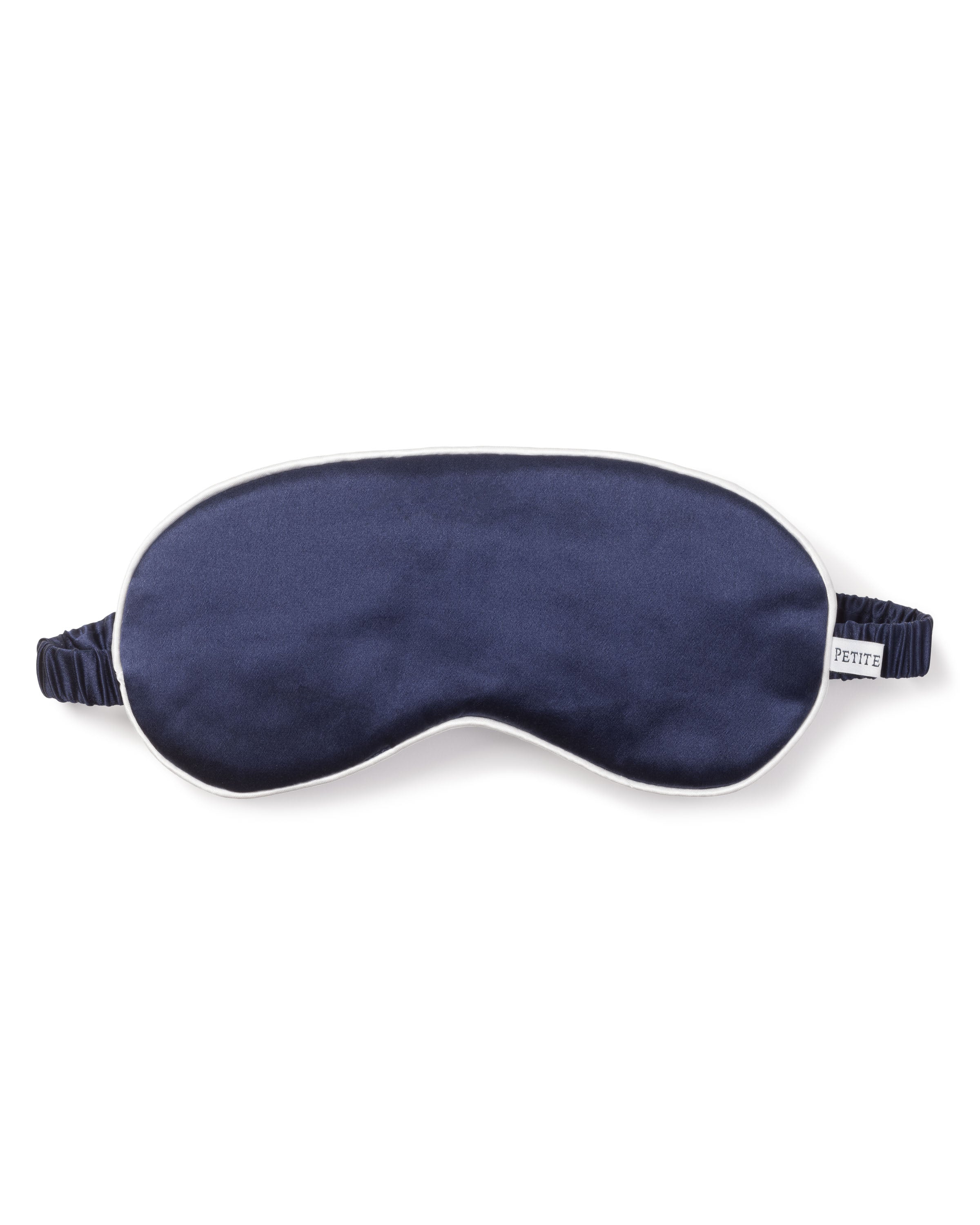 The Adults Silk Sleep Mask in Navy by Petite Plume features white piping, an elastic strap, and a PETITE tag on the right side. Its luxurious design on a white background makes it an exceptional sleep mask choice.