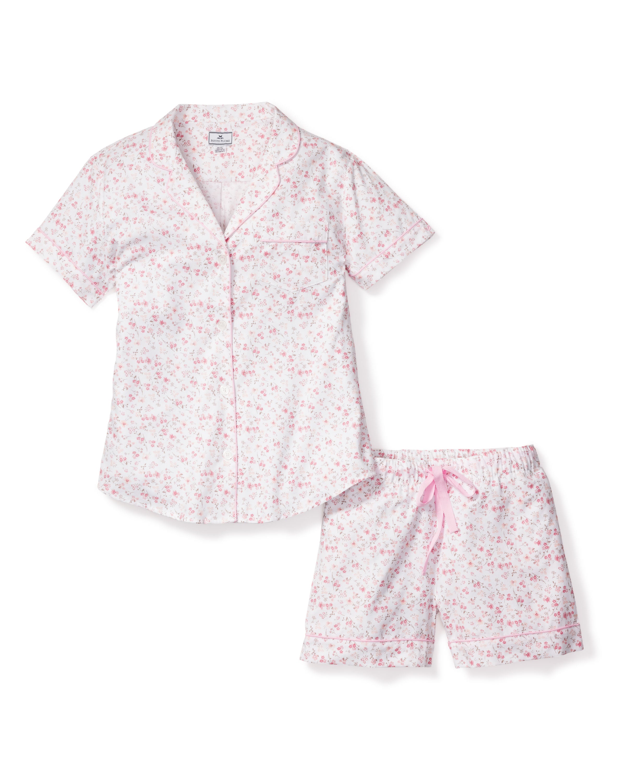 Indulge in luxurious sleepwear with Petite Plumes Womens Twill Short Sleeve Short Set in Dorset Floral. This 100% cotton, white set features a pink floral pattern, short-sleeve button-up shirt with a chest pocket, and comfy shorts with a pink drawstring waistband.