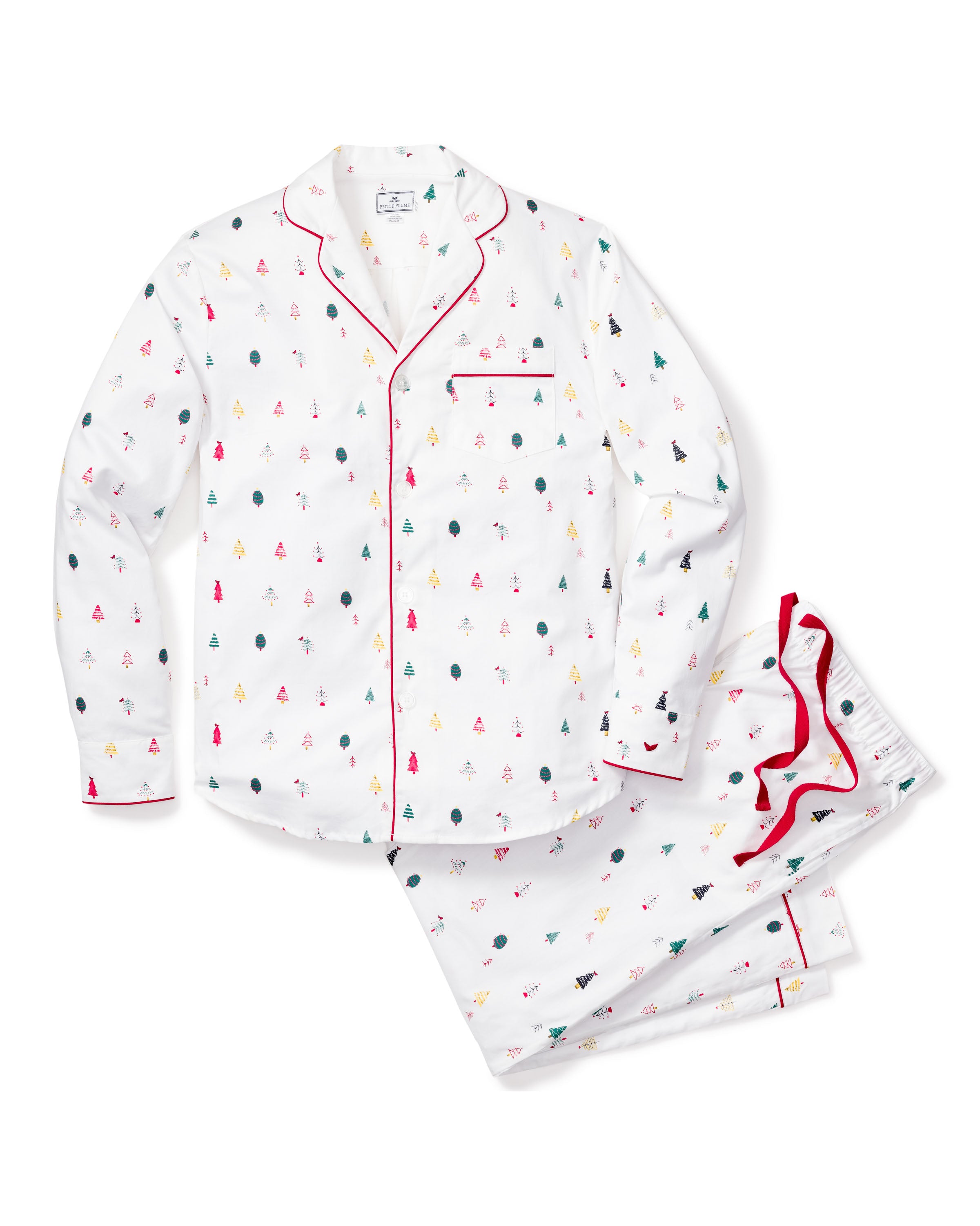 The Mens Twill Pajama Set in Merry Trees by Petite Plume includes a white button-up shirt and pants made from top-quality cotton, featuring small red, green, and black tree patterns. The shirt has a chest pocket and red piping, while the pants offer an elastic waistband for comfort—perfect for Christmas.