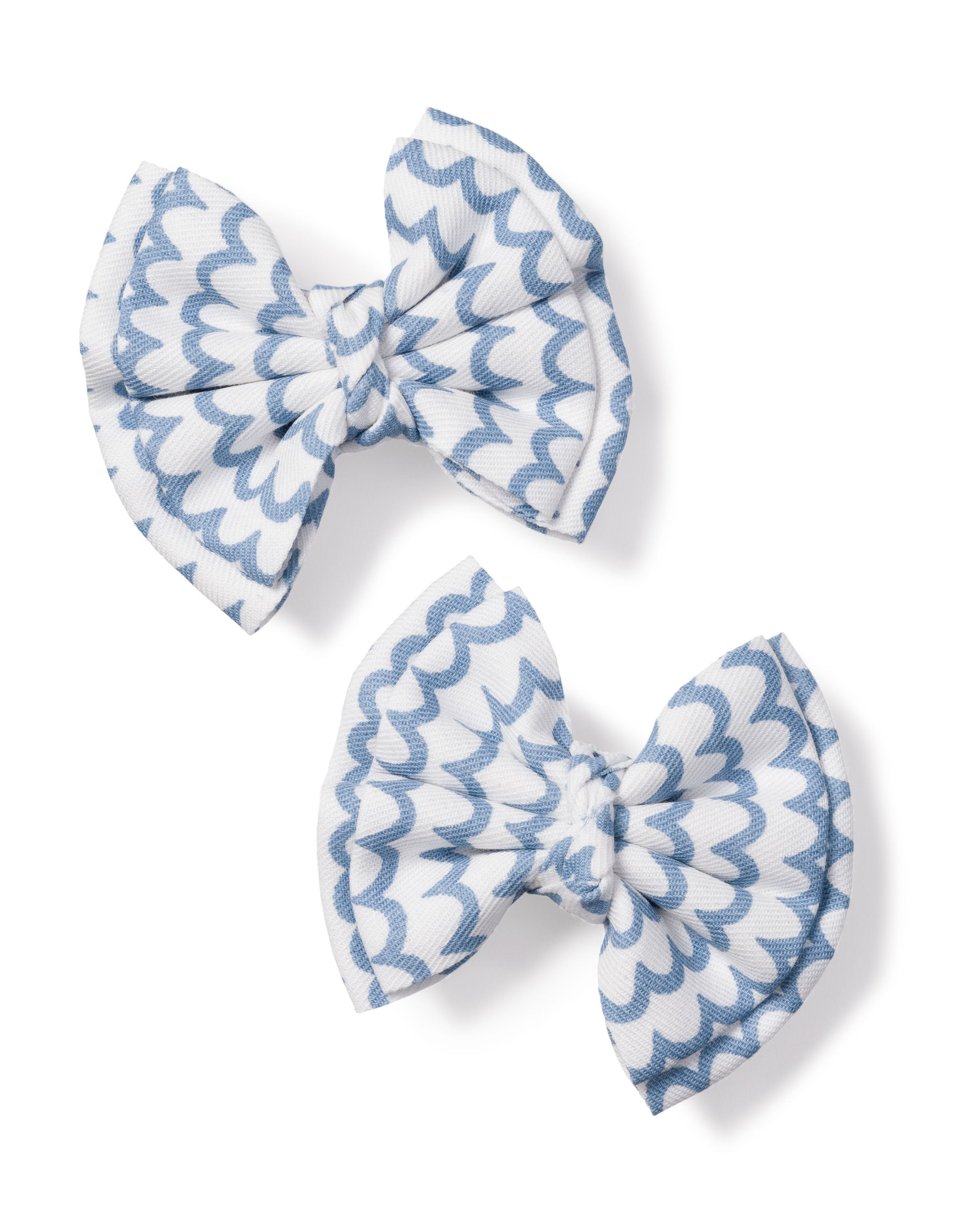 The Girls Hair Bows in La Mer by Petite Plume, featuring charming white and light blue scalloped patterns, make the perfect accessory for girls. Positioned diagonally on a plain white background, these elegant bows add a touch of sophistication to any outfit.