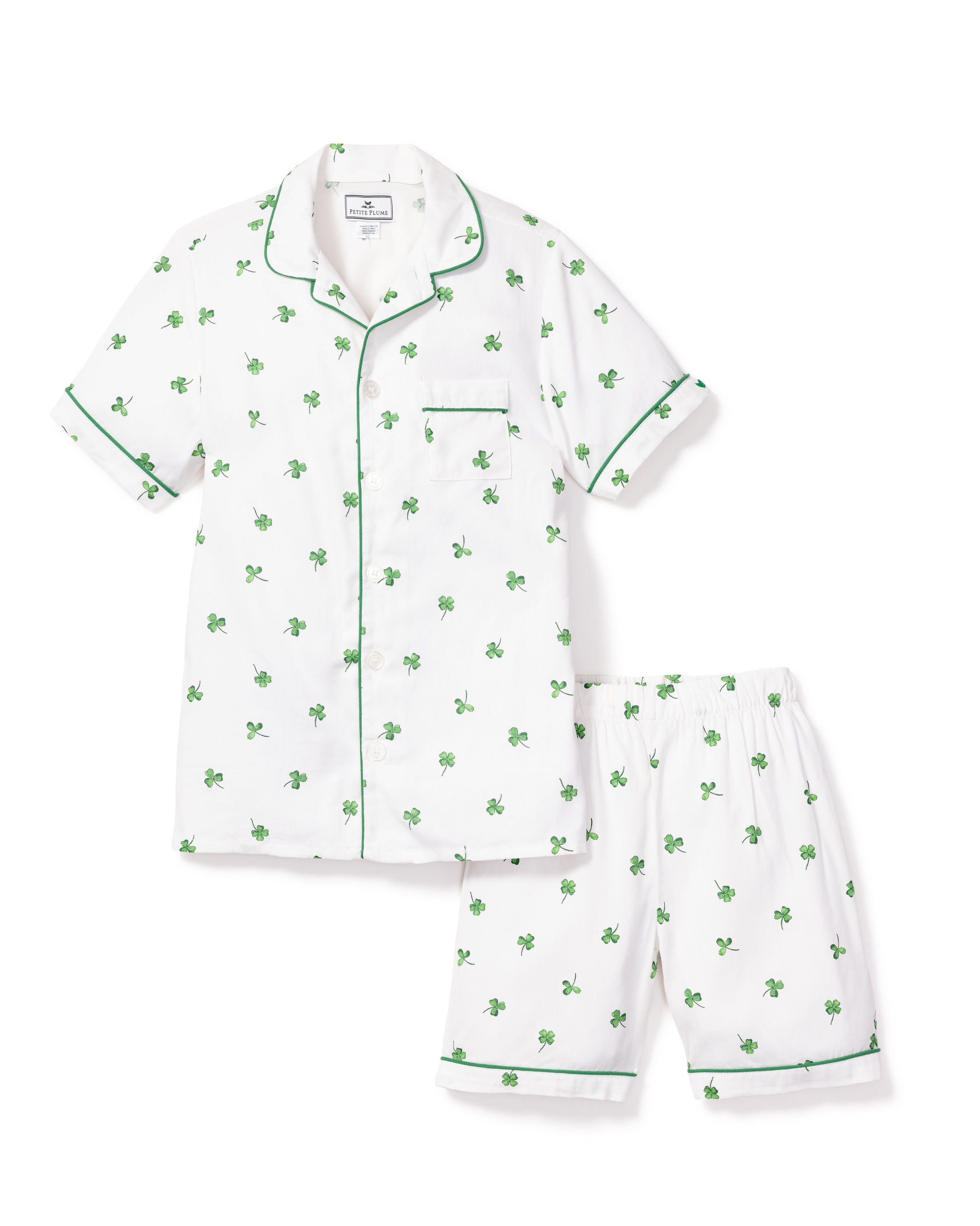 From the Shamrocks Collection by Petite Plume, the Kids Twill Pajama Short Set features a white button-up top and matching shorts adorned with green clover patterns and elegant green piping.