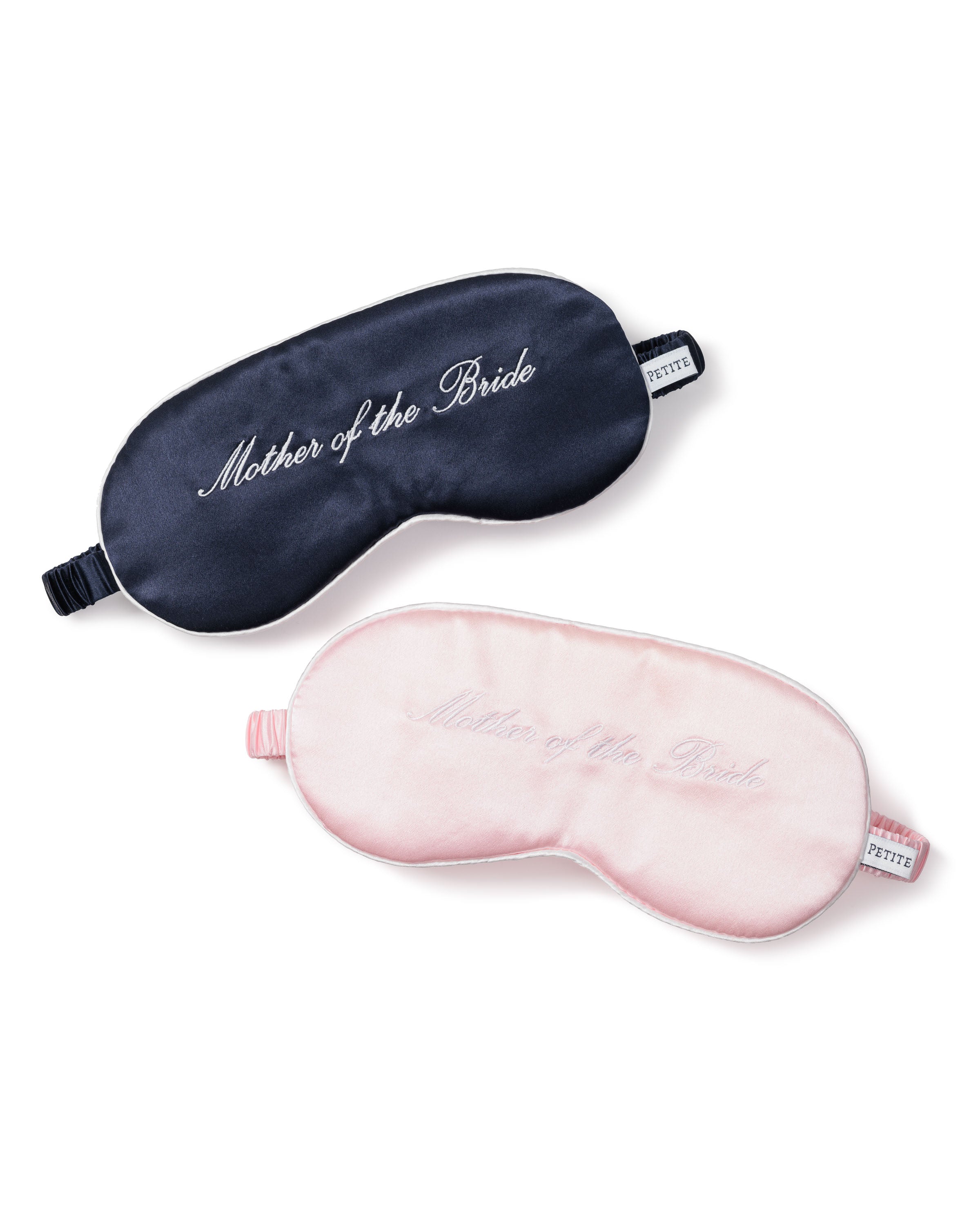 Displayed are two elegant sleep masks from Petite Plume, perfect as a wedding gift. The top is navy blue silk with Mother of the Bride in white, and the bottom is light pink with the same embroidery. Both feature elastic straps for comfort.