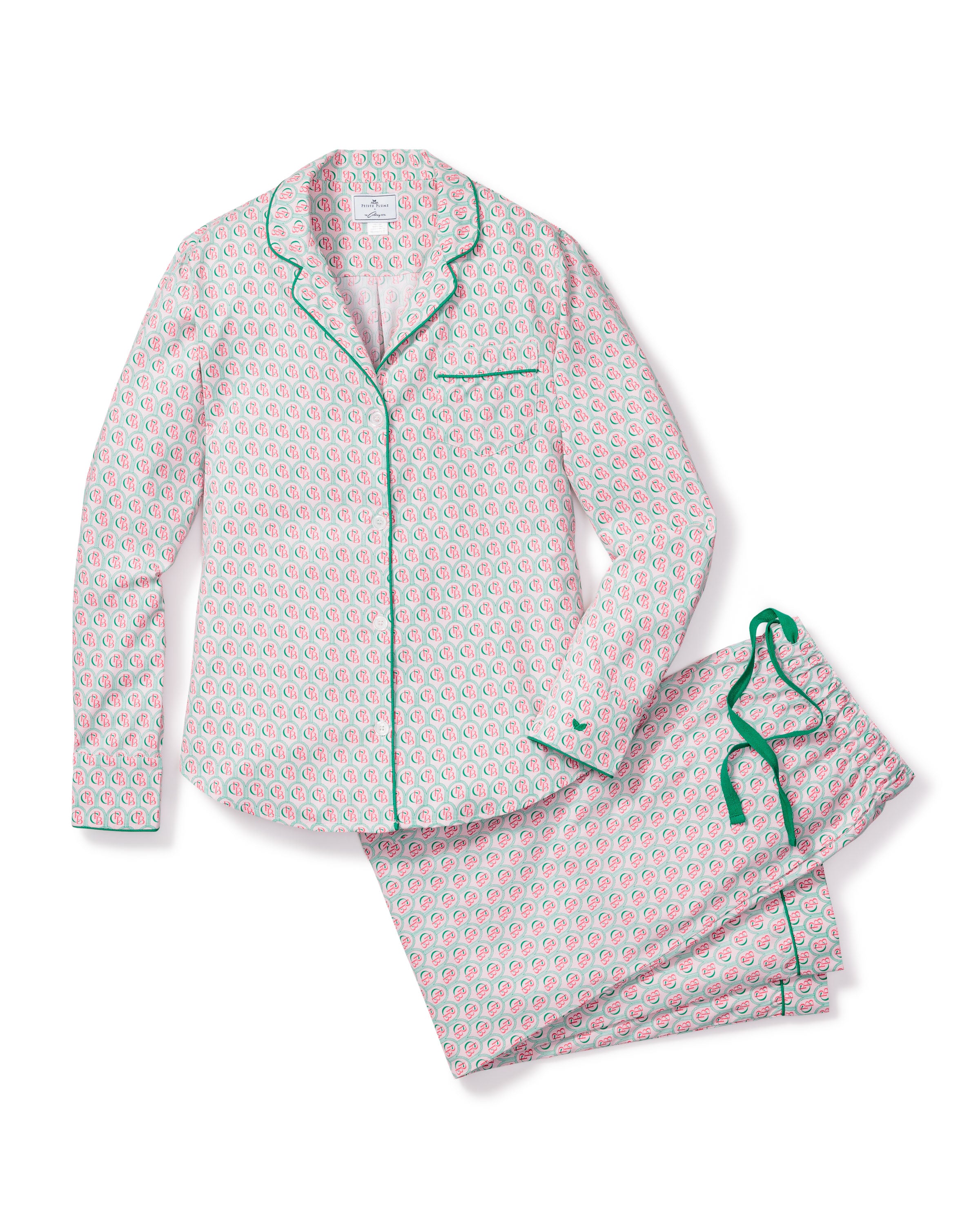 The Colony Hotel x Petite Plume Womens Exclusive Print Pajama Set features a pink and green floral pattern. The top has a collar, button-down design, and green piping, while the pants include a green drawstring. Both pieces are shown flat on a white background.