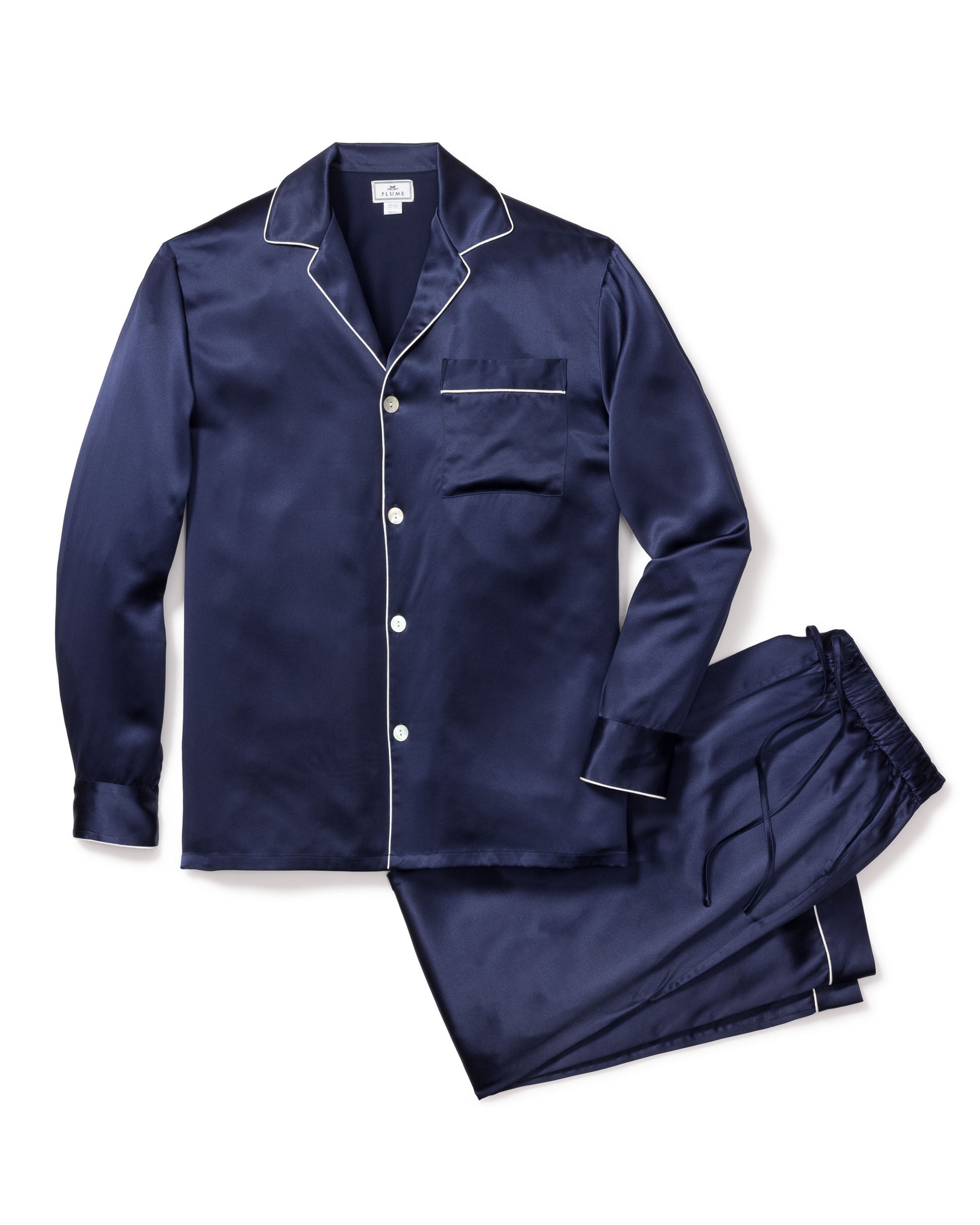 The Mens Silk Pajama Set in Navy by Petite Plume includes a navy silk long-sleeve button-up shirt with white piping on the collar, cuffs, and pocket. The matching drawstring pants also feature white piping. This luxury sleepwear is machine-washable for easy care.