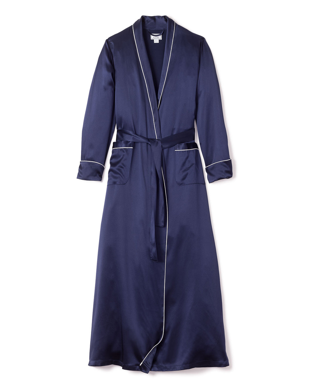 The Womens Silk Long Robe in Navy by Petite Plume epitomizes luxury sleepwear with its white piping, shawl collar, long sleeves, matching waist belt, and two front pockets adorned with white trim for added sophistication.