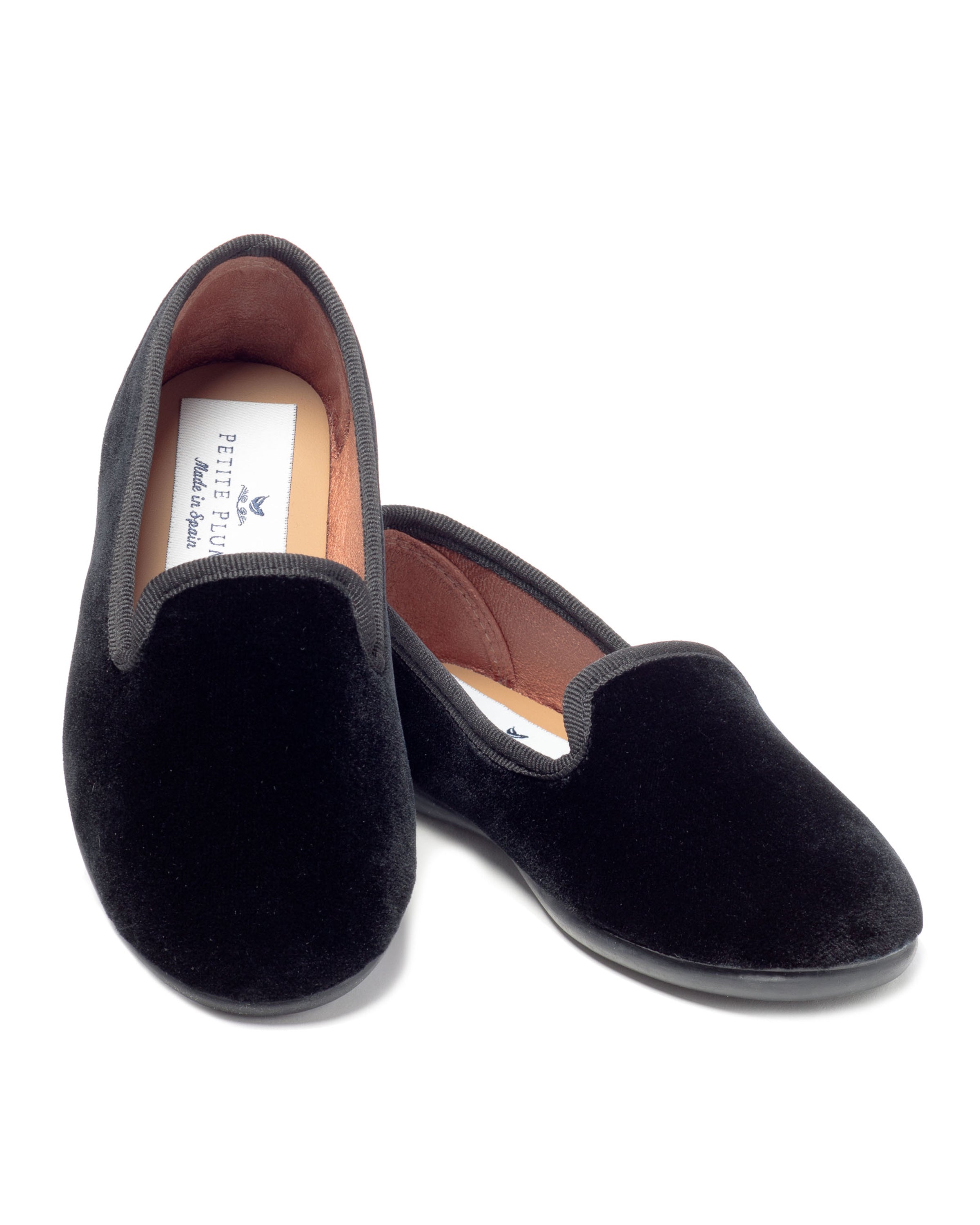A pair of Petite Plumes Kids Hamptons Loafers in black velvet, featuring brown lining, is displayed with one angled slightly in front. Partially visible are the white branded insoles.