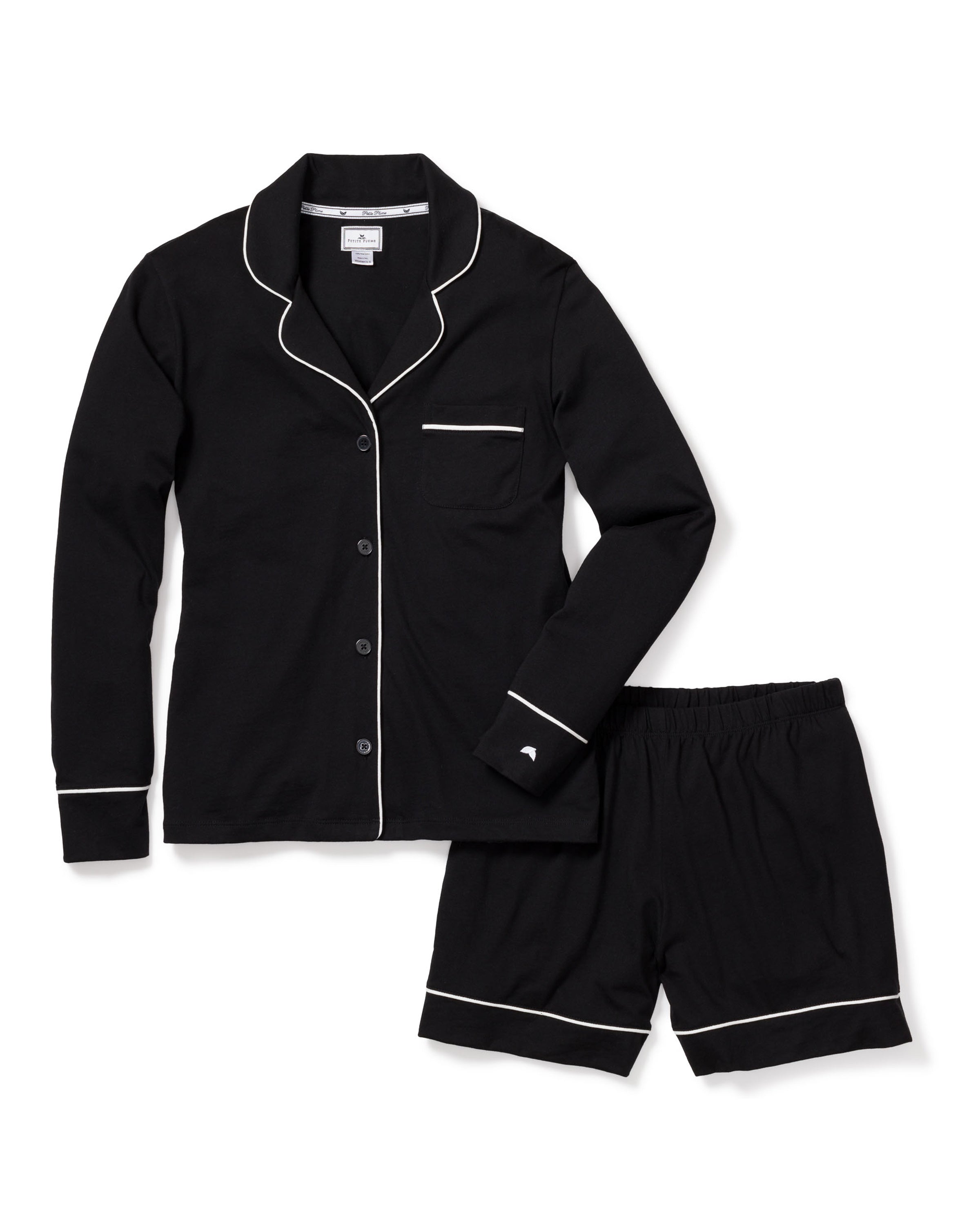 The Womens Pima Short Set in Black by Petite Plume is crafted from luxurious Peruvian Pima cotton and features a long-sleeve button-up top with white piping and a chest pocket, along with matching shorts that have an elastic waistband.